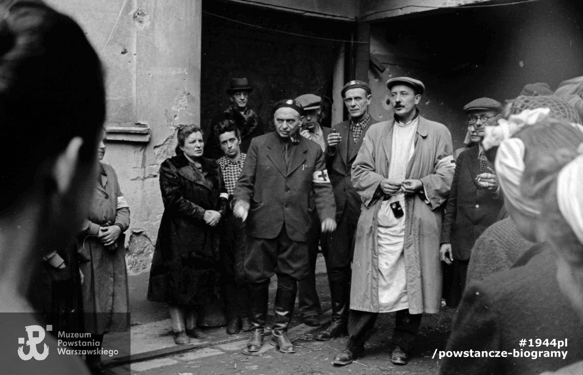 Fotografia z Powstania Warszawskiego. Podwórze szpitala polowego przy Wspólnej 27. Grupa lekarzy w otoczeniu współpracowników. W środku w białym kitlu mjr dr Feliks Michalec "Doktór Piotr", po jego prawej kpt. dr Tadeusz Gerwel "Orda" i ppłk dr Tadeusz Bętkowski "Tata" (z fajką). Fot. ze zbiorów Muzeum Powstania Warszawskiego, sygn. MPW-IN/3772