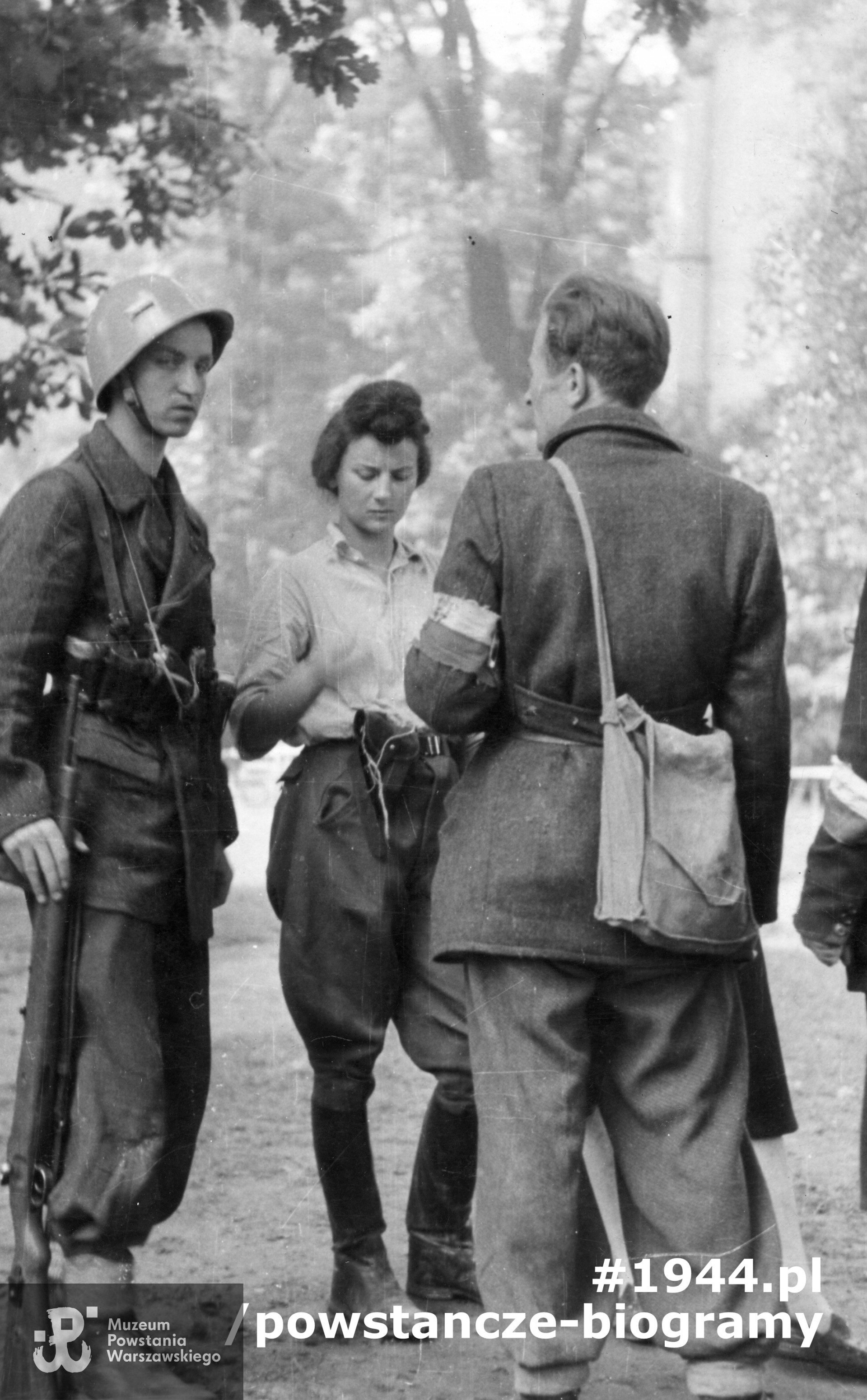 Fotografia z Powstania Warszawskiego. Śródmieście Północne, pl. Dąbrowskiego. Troje powstańców z 2. plutonu im. por. "Rygla" 4. kompanii zgrupowania "Bartkiewicz". Od lewej: st. strz. Alfred Wróblewski "Szary", łączniczka fotografka strz. Irena Kummant-Skotnicka "Luga" oraz jej brat por. Leopold Kummant "Ryski". Autorem zdjęcia jest Andrzej Ancuta. Fot. ze zbiorów Muzeum Powstania Warszawskiego, sygn. MPW-IK/2667,  MPW-IK/2772