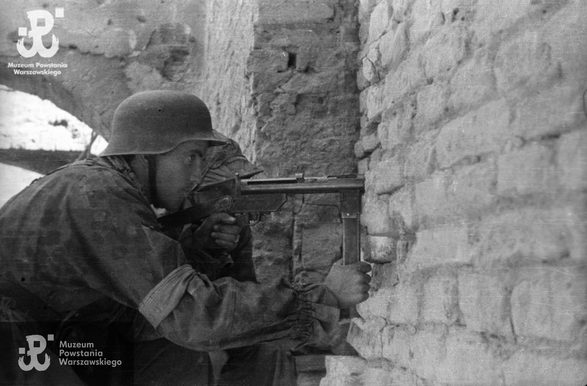 Fotografia z Powstania Warszawskiego. Stare Miasto, ulica Ślepa. Kpr. Jerzy Sikorski „Sixton” z pistoletem maszynowym „Błyskawica” na stanowisku strzeleckim między ulicą Ślepą a Podwalem przy placu Zamkowym. Za nim st. strz. Jerzy Łyczkowski „Łan”. Autorem zdjęcia jest Wiesław Chrzanowski „Wiesław”. Ze zbiorów Muzeum Powstania Warszawskiego, sygn. MPW-IN/3242
