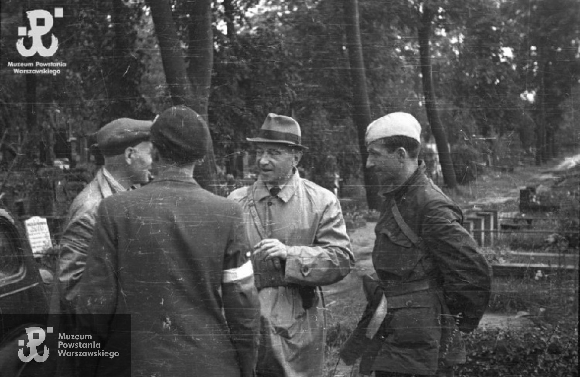 Wizytacja płka Kazimierza Iranka Osmeckiego "Makary" (w kapeluszu), szefa Oddziału II KG AK na cmentarzu ewngelicko-augsburskim. W rozmowie uczestniczą mjr Alfons Kotowski "Okoń" (po lewej) i por Stanisław Jankowskim "Agaton" (po prawej). Zdjęcie autorstwa Stefana Bałuka, ze zbiorów Fototeki MPW , sygnatura<a href=" http://www.1944.pl/galerie/fototeka/foto/7905/autor/126"> MPW-IS/131</a>