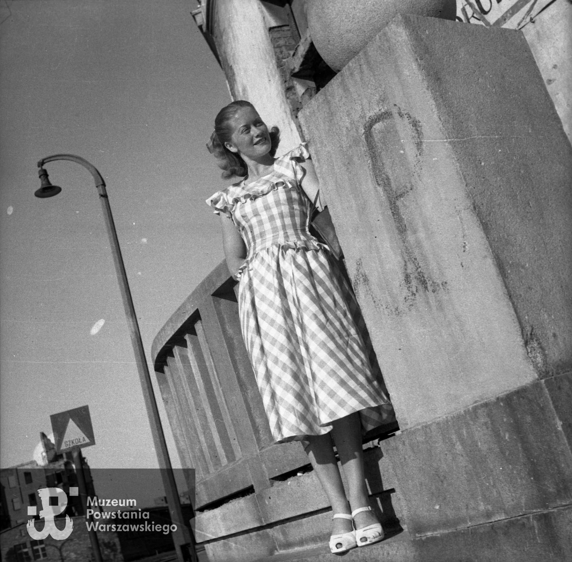 Fotografia z okresu powojennego. Warszawa, Śródmieście Południowe. Aktorka Alina Janowska (w Powstaniu Warszawskim łączniczka "Alina" w batalionie "Kiliński") przy balustradzie cukierni Lardellego przy ulicy Polnej 30. Na postumencie "kotwica" - znak Polski Walczącej, namalowana przez Aleksego Dawidowskiego "Alka". Autorem zdjęcia jest Edward Dziewoński. Fot. ze zbiorów Muzeum Powstania Warszawskiego, sygn. MPW-IN/4230
