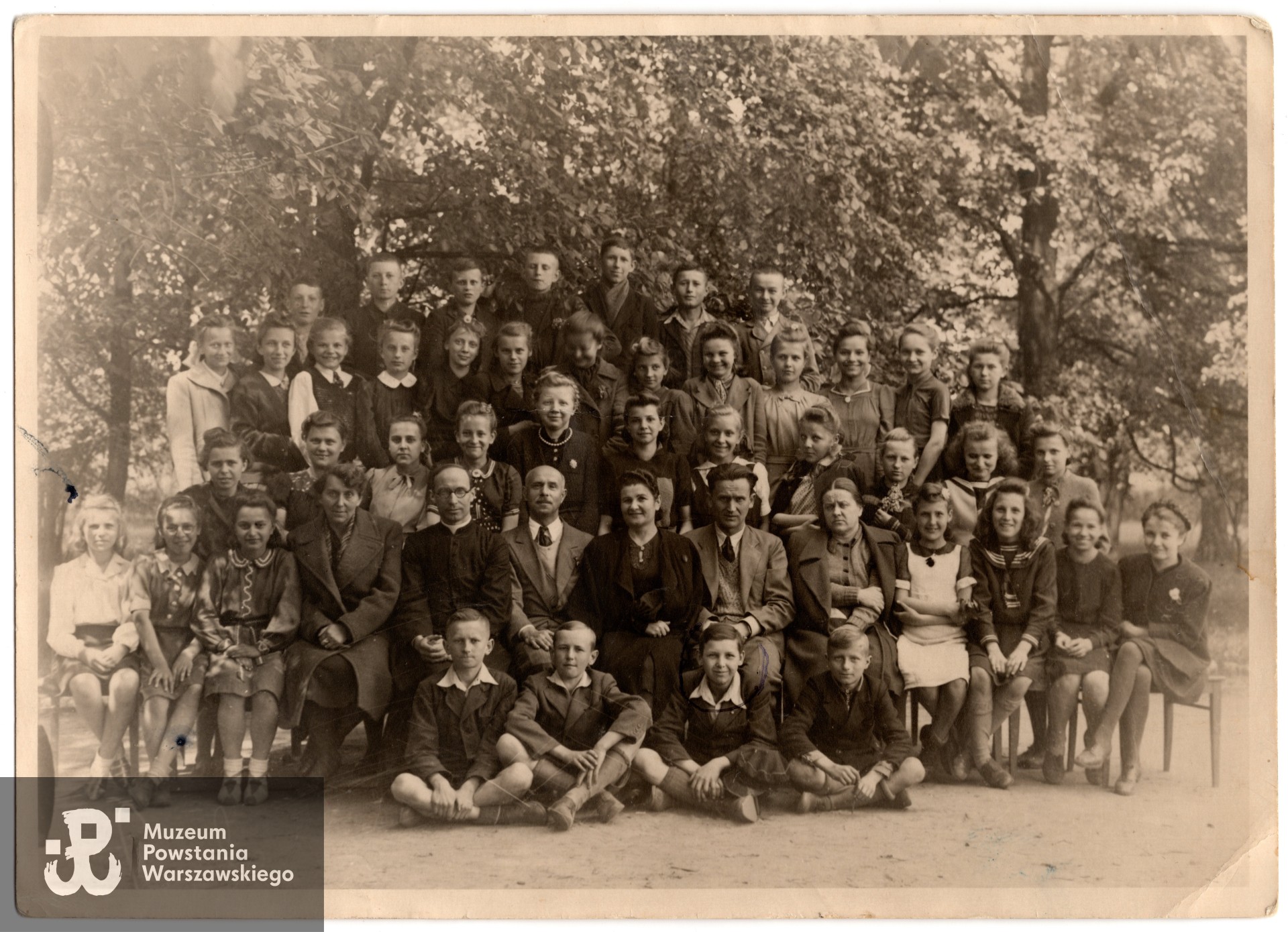  Fotografia szkolna, 1943 rok. Leonard Kapiszewski siedzi w pierwszym rzędzie, przed nauczycielami (zaznaczony w kółku). Fot. ze zbiorów prywatnych  Powstańca, udostępnił p. Leonard Kapiszewski ps. Ryś.