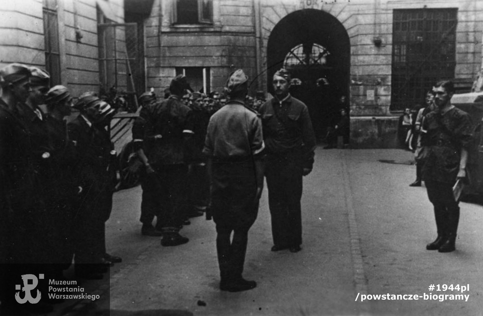 Fotografia z Powstania Warszawskiego. Śródmieście Północne. Odprawa wart w kwaterze sztabu IV Rejonu Obwodu Śródmieście mjr. "Zagończyka" na podwórzu kamienicy Marszałkowska 125. Odbiera ppor Oskar Schmidt "Słoń", melduje kpr. pchor. Krystyn Plewko "Krystyn", z prawej ppor. rez. Stefan Nast "Orlicz", dowódca plutonu saperów "Zagończyka". Autorem zdjęcia jest Zygmunt Kukieła „Zetka”. Fot ze zbiorów Muzeum Powstania Warszawskiego,  MPW-IP/2474