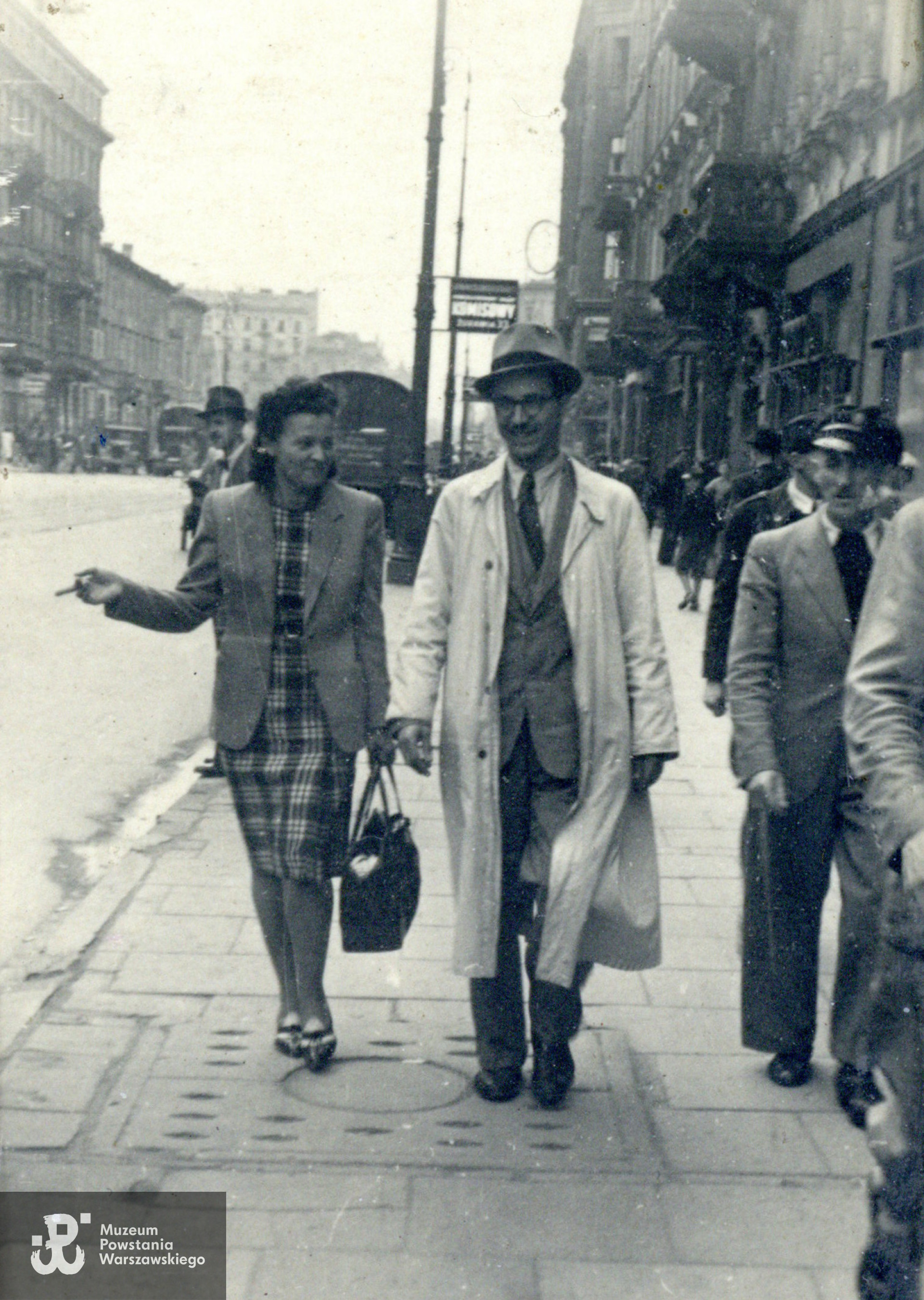 Mieczysław Łowiński i Krystyna Czosnowska, po mężu Łowińska. Fotografia wykonana w Warszawie w okresie okupacji niemieckiej na ul. Marszałkowskiej pomiędzy Żurawią a Nowogrodzką po stronie parzystej. W oddali po lewej Marszałkowska 99 róg Nowogrodzka i Marszałkowska 101 róg Jerozolimskie (willa Marconiego). W perspektywie brak natomiast wieży Dworca Wiedeńskiego, która została zniszczona we wrześniu 1939 i rozebrana niedługo potem. Fot. ze zbiorów rodzinnych p. Ewy Łowińskiej, córki Powstańca. Skany wykonano w Archiwum Muzeum Powstania Warszawskiego, 03/2024