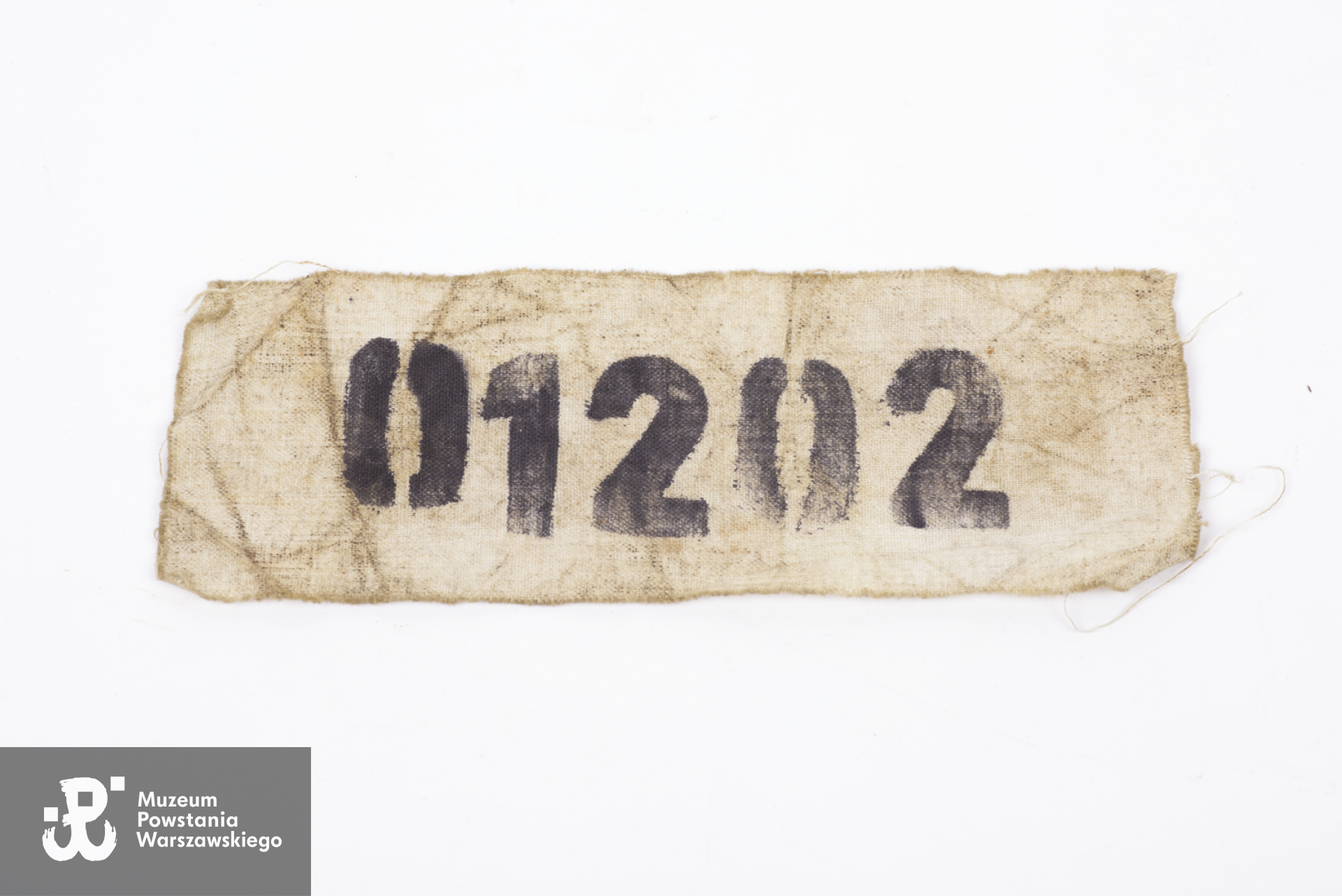 Numer płócienny więźnia obozu No. 01202 noszony na plecach, należący do kpt. Władysława Klęka oficera Armii Krajowej skazanego na śmierć przez sąd wojskowy SS w niemieckim obozie jenieckim Sandbostel.  Zbiory Muzeum Wojska Polskiego w Sydney