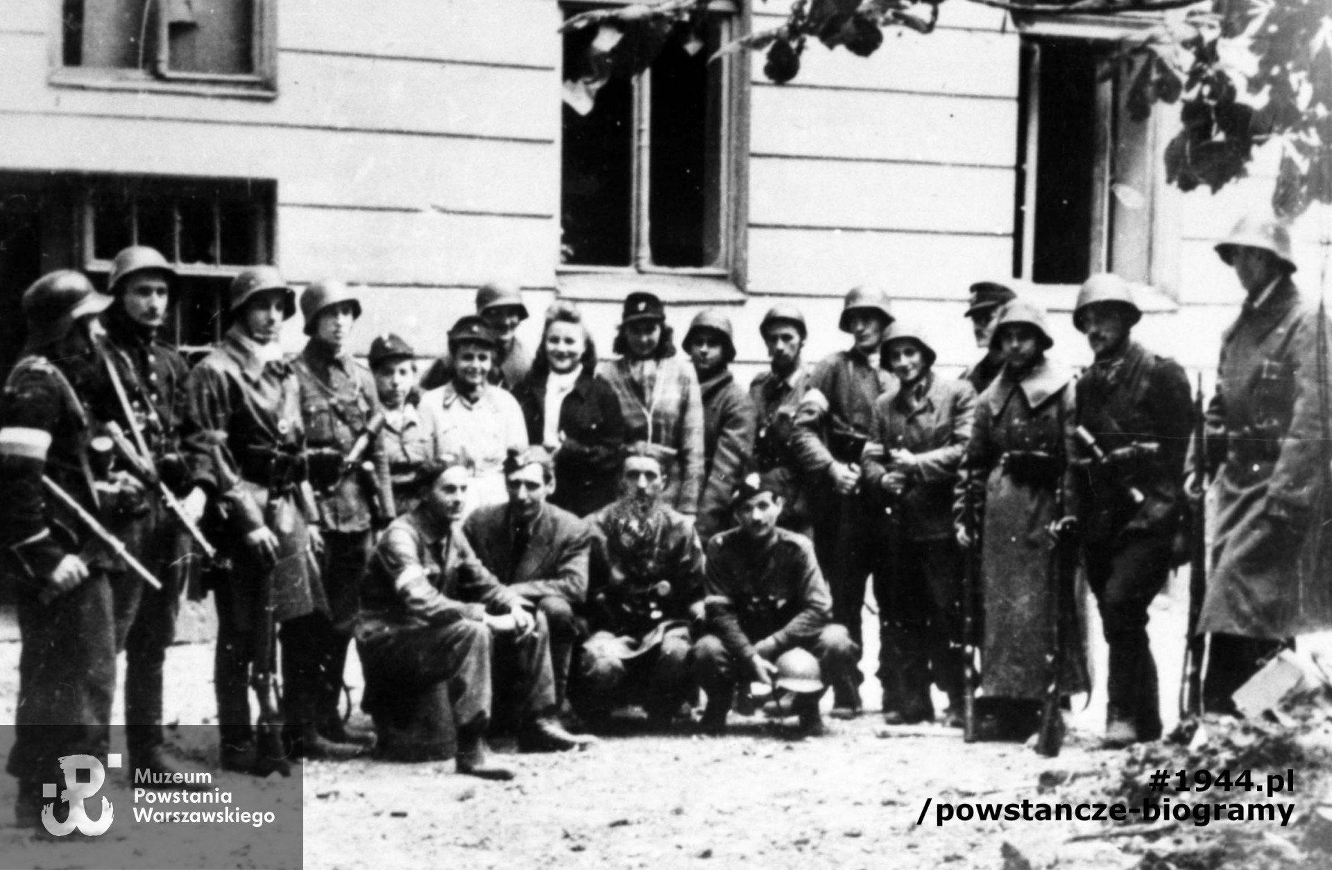Zdjęcie z października 1944 r. Grupa żołnierzy plut. NSZ "Sikora" kompanii "A" batalionu osłonowego AK przed kamienicą w Śródmieściu Południowym. Stoją: plut. pchor. Jan Podhorski "Zygzak" - siódmy od lewej, kpr. Włodzimierz Jakimowicz "Szczapa" - dziesiąty od lewej, kpr. pchor. Henryk Dutkowski "Kosowski" - czwarty od prawej. Klęczą od lewej: zbrojmistrz Józef Krynojewski, NN, ppor. Henryk Czapczyk "Mirski", "Śmigły" Pałaszewski. Autorem zdjęcia jest Henryk Świercz "Świerszcz". Fot. ze zbiorów Muzeum Powstania Warszawskiego, sygn. MPW-IN/3536