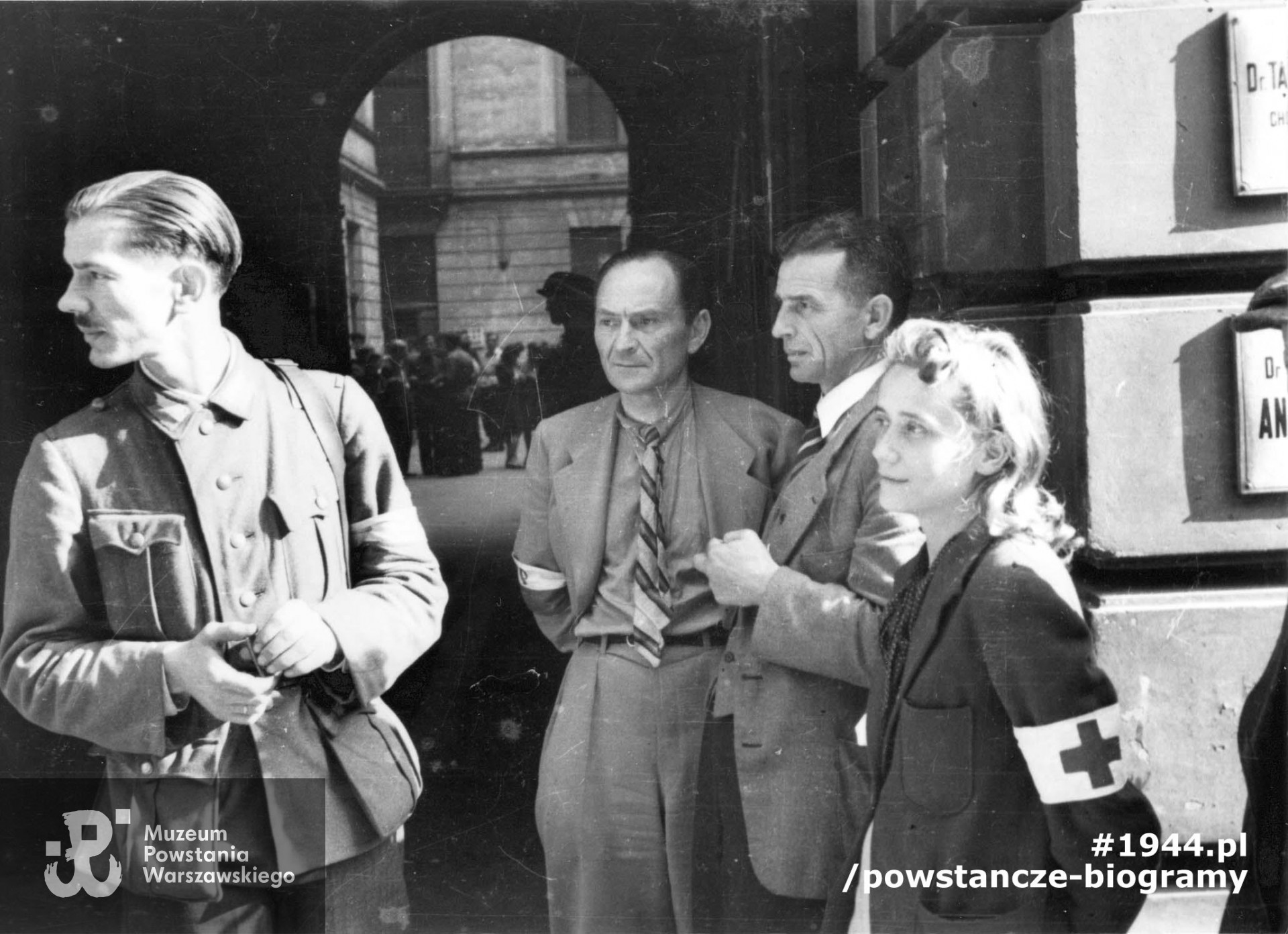 Fotografia z Powstania Warszawskiego. Śródmieście Północne. Grupa powstańców w bramie kamienicy przy ul. Moniuszki 11. Od prawej: sanitariuszka Wanda Regenciak "Alicja", mjr Tadeusz Andrzej Grochowski "Fidelis" oraz prawdopodobnie  kpt. Jan Łączyński "Tadeusz". Pierwszy z lewej stoi bratanek Tadeusza - kpr. Stanisław Grochowski. Identyfikacja Stanisława w oparciu o informacje p. Zofii Szmid, córki Wandy Regenciak - Grochowskiej - Święcińskiej. Autorem zdjęcia jest Eugeniusz Lokajski "Brok". Fot. ze zbiorów Muzeum Powstania Warszawskiego, sygn. MPW-IN/201