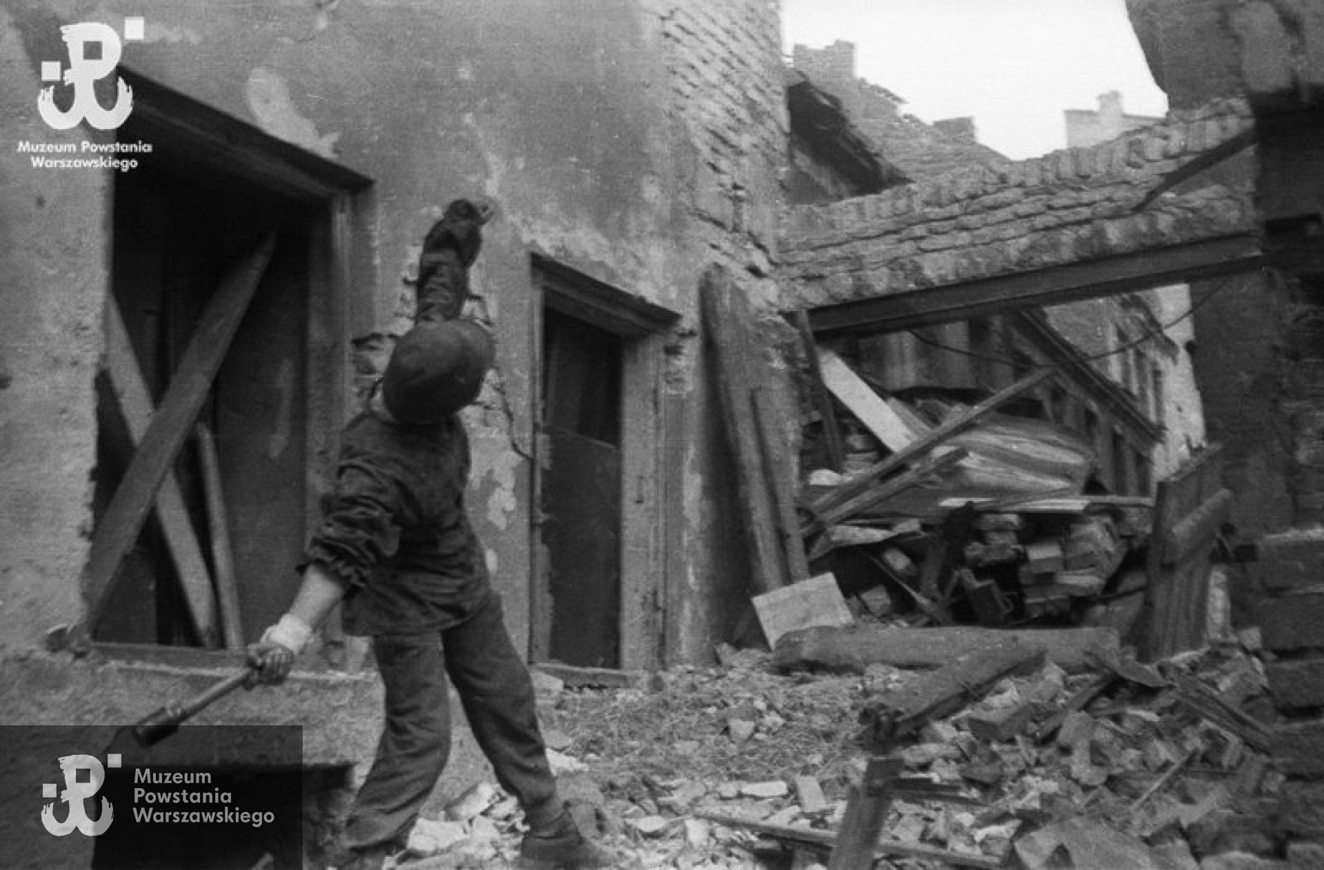 Fotografia z Powstania Warszawskiego. Stare Miasto, ulica Ślepa. Ppor. Jerzy Siwiec „Jur” z kompanii „Anna” Batalionu „Gustaw” z granatem trzonkowym StiHgr-24 przed „bramką” na ulicy Ślepej. „Jur” rzuca w kierunku pozycji niemieckich na placu Zamkowym. Autorem zdjęcia jest Eugeniusz Haneman. Fot. ze zbiorów Muzeum Powstania Warszawskiego, sygn. MPW-IN/3253