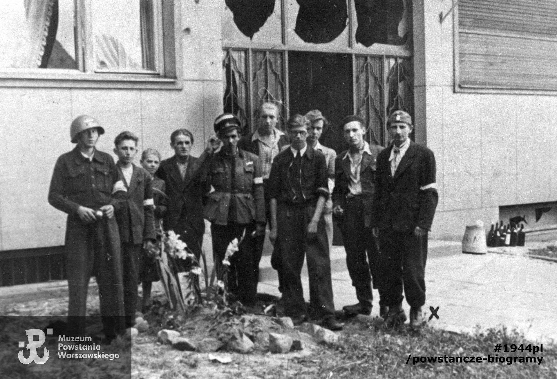 Fotografia z Powstania Warszawskiego. Powiśle. Grupa powstańców przy grobie na trawniku przed budynkiem przy ulicy Konopczyńskiego 3, gdzie mieścił się szpital polowy. Pierwszy z prawej kpr. "Pawłowski" inż. Jerzy Seredyński. Fot. ze zbiorów  Muzeum Powstania Warszawskiego, sygn. MPW-IK/1505, zbiór Stanisława Kopfa