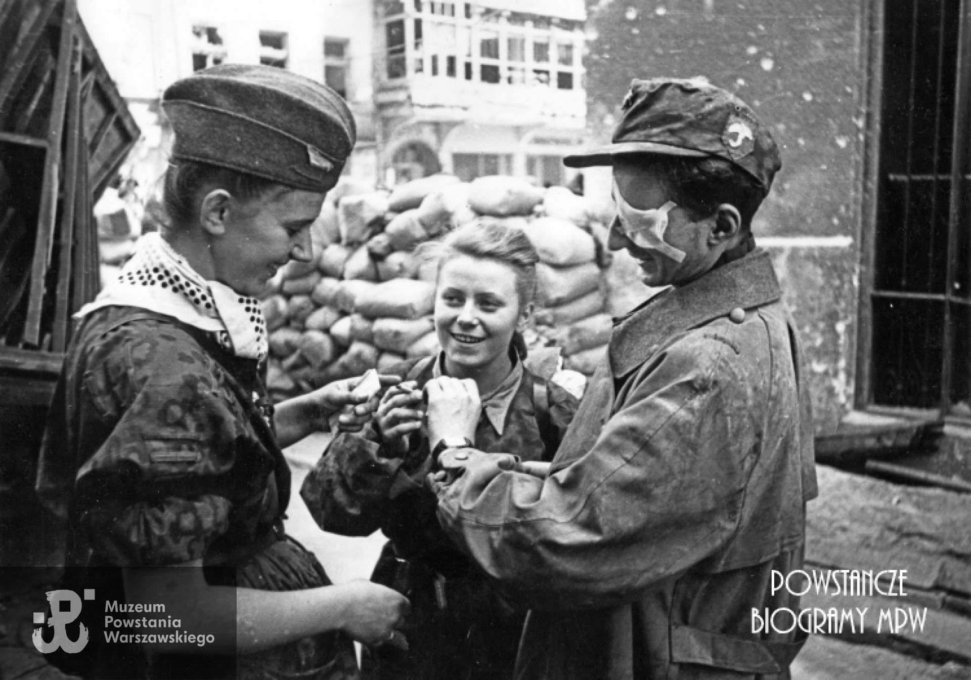 "Parasolarze" po wyjściu z kanału na ul. Wareckiej 1.09.1944 r. Zwracają uwagę: znak baonu naszyty na niemiecką czapkę polową i apaszka dziewczyny. Różnokolorowe chustki przewiązane pod szyją, w czasie walk na Starym Mieście stały się znakiem rozpoznawczym oddziałów, jednolicie ubranych w zdobyczne "panterki". Każdy oddział używał chust w innym kolorze. Od lewej stoją: nierozpoznana łączniczka lub sanitariuszka, w środku "Kama" (Maria Stypułkowska-Chojecka), po prawej ranny kpr. pchor. "Krzych" (Krzysztof Palester - poległ 21.09.1944 na Górnym Czerniakowie). W tle widoczny Hotel "Savoy" ul. Nowy Świat 58. Fot. Joachim Joachimczyk. Ze zbiorów Fototeki MPW, sygn. MPW-IK/2960