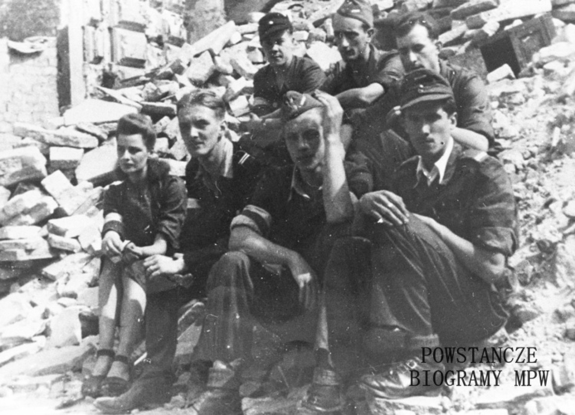 Grupa powstańców -  Kompania "Grażyna" - "OS-y" (oddział specjalny) na Świętokrzyskiej 17. Od prawej : pierwszy "Wypad" (Witold Kieżun), trzeci "Turek" (Staś Kiciński) i Danka Megreczyńska. Fot. udostępnione z archiwum prywatnego Marii Pajzderskiej. Zdjęcie także w zbiorach Muzeum Powstania Warszawskiego, sygn. MPW-IH/4758