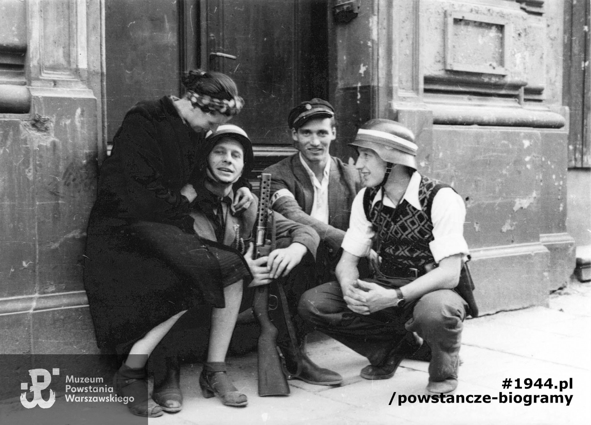 Fotografia z Powstania Warszawskiego. Śródmieście Północne. Grupa Powstańców z kompanii "Koszta" przy bocznym wejściu do gmachu Filharmonii przy ul. Jasnej 5. Od lewej: Zofia Domańska "Zocha" (siostra autora zdjęć), por. Roman Rozmiłowski "Zawada", trzymający niemiecki zdobyczny pistolet maszynowy MP 28 II "bergmann", ppor. Stanisław Kuśpit "Kruk" i kpr. pchor. Antoni Tuleja "Niedźwiedź". Autorem zdjęcia jest Eugeniusz Lokajski "Brok". Fot. ze  zbiorów Muzeum Powstania Warszawskiego, sygn. MPW-IN/42