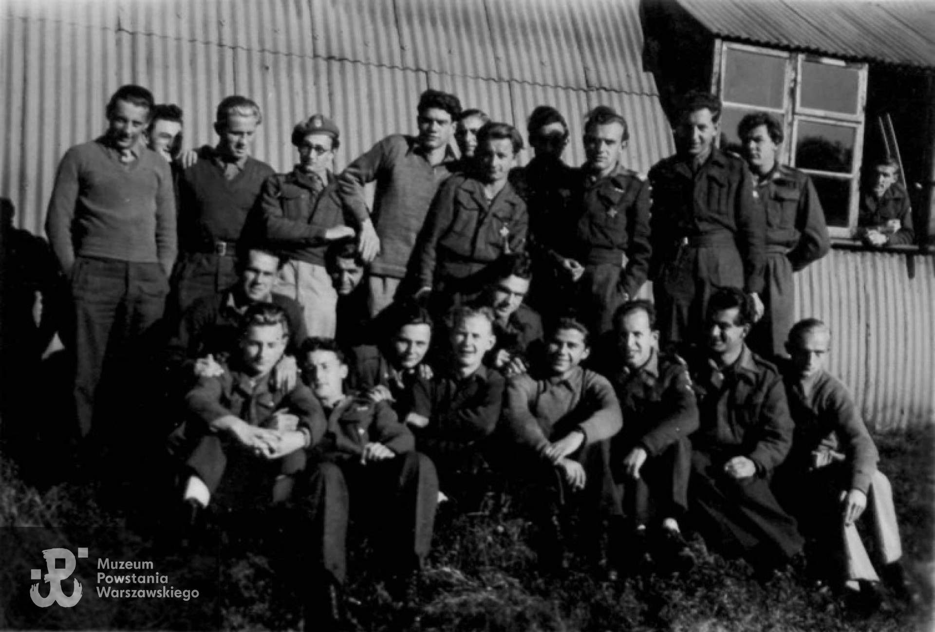 Rożne drogi prowadziły uczniów do Gimnazjum i Liceum 3 Dywizji Strzelców Karpackich w Bodney Airfield Camp. Jedni przeszli przez Tobruk. Inni przez ZSRR, Irak, Palestynę, potem razem przez Monte Cassino, Anconę, Bolonię... Wielu było z AK, przeszło Oświęcim, czy Powstanie Warszawskie.  Również byli i zmobilizowani do armii niemieckiej, którzy przy pierwszej okazji dołączyli do swoich w II Korpusie Polskim. Na zdjęciu II klasy licealnej Krzysztof Głuchowski siedzi w pierwszym rzędzie, pierwszy od lewej. Jesień 1946. Fot. z archiwum rodzinnego Krzysztofa Głuchowskiego.