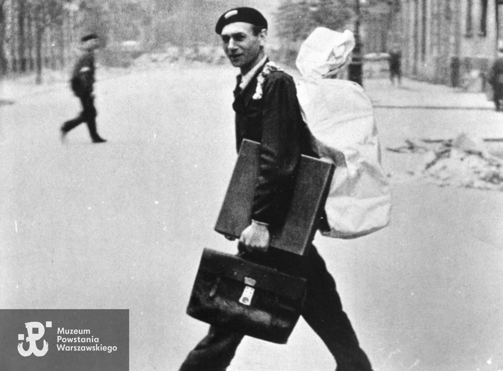 Fotografia z Powstania Warszawskiego. Śródmieście Północne. Operator i montażysta Wacław Kaźmierczak na ul. Szpitalnej podczas przenoszenia materiałów filmowych i sprzętu montażowego z Powiśla do Kina  Palladium  na ul. Złotej 7/9. Trzecia dekada sierpnia 1944. Autorem zdjęcia jest Antoni Wawrzyniak. 