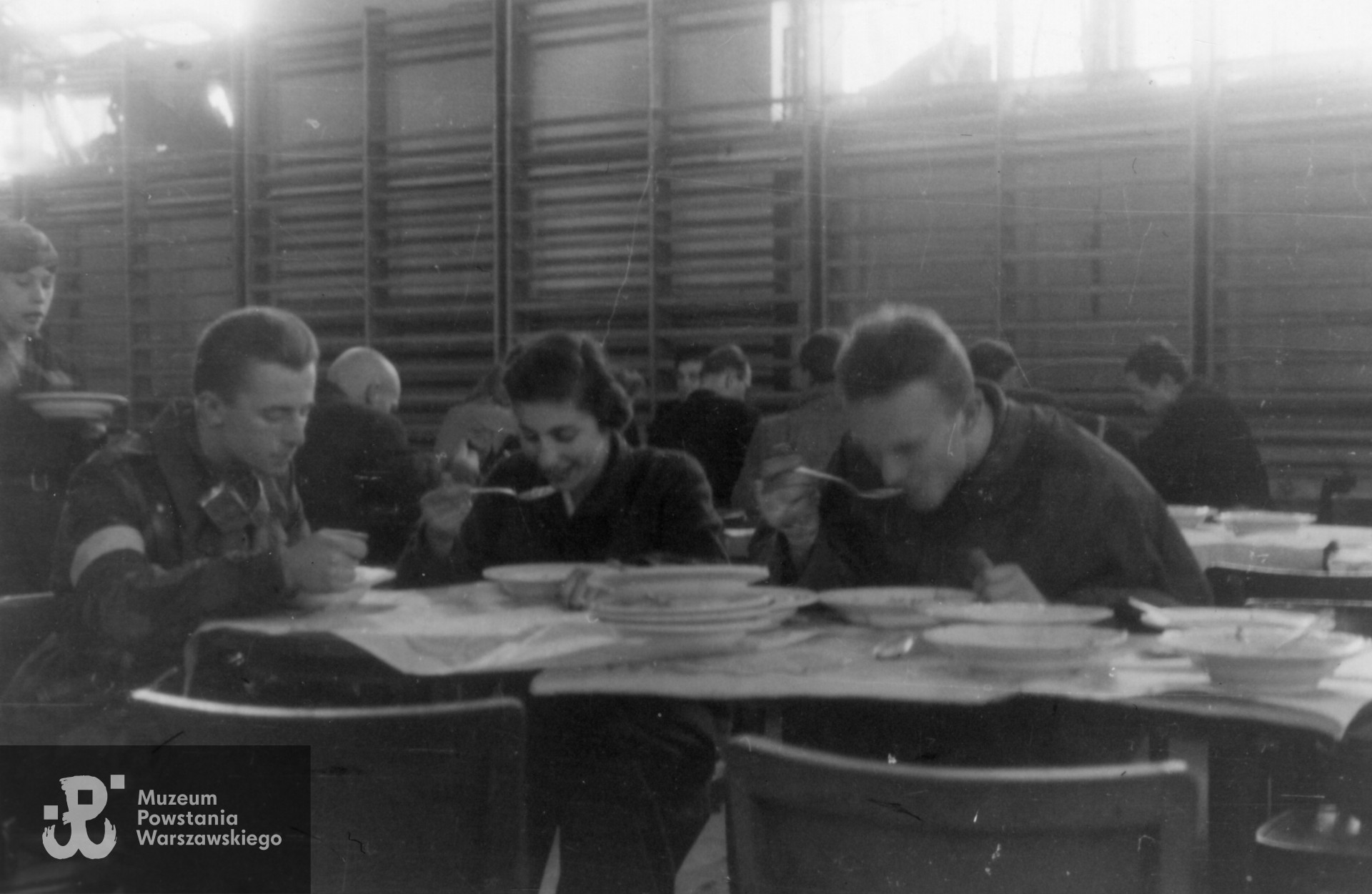  Śródmieście Południowe. Żołnierze 3. kompanii "Redy" batalionu "Miłosz" podczas posiłku w sali gimnastycznej YMCA ( ul. Konopnickiej 6).  Od lewej sierż pchor. Juliusz Pietrzykowski "Teddy", plut. Maria Myszkowska "Myszka" i kpr. pchor. Stanisław Szabłowski "Witeź". Fot. Wojciech Marczyński "Bogusław". Ze zbiorów Muzeum Powstania Warszawskiego, MPW-IK/2439.
