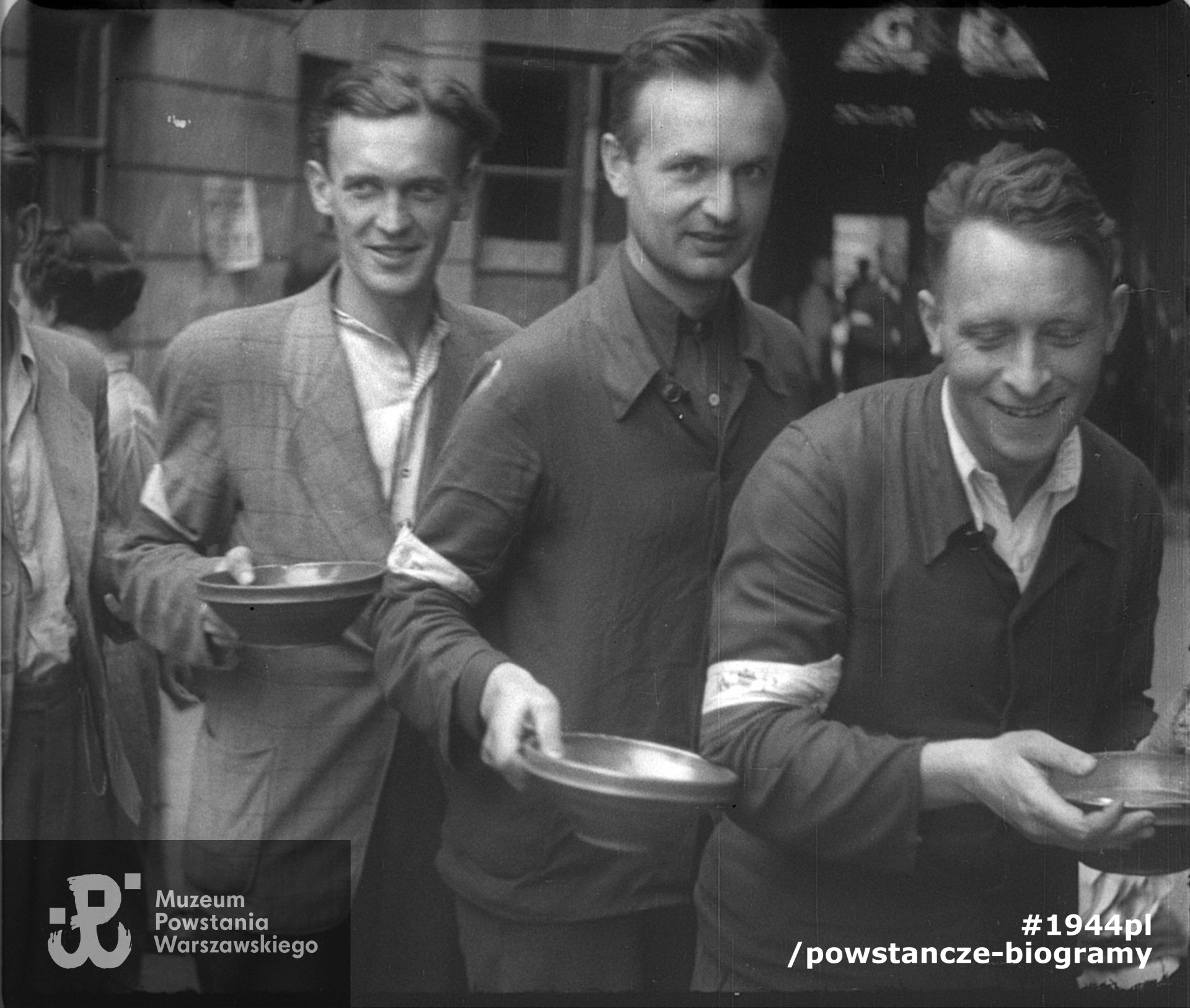 Stołówka powstańcza na podwórzu kamienicy przy ul. Szpitalnej 8. Od lewej: kpr. pchor. Bernard Wojciech Mencel „Paweł”, członek patrolu megafonowego „Chwaty” (poległ 13.09.1944 r. przy ul. Marszałkowskiej),  por. Józef Marian Sosnowski, ps. Brzeziński, Tadeusz Mikulski „Krasicki”. Zdjęcie filmowe z okresu Powstania. Ze zbiorów Muzeum Powstania Warszawskiego.