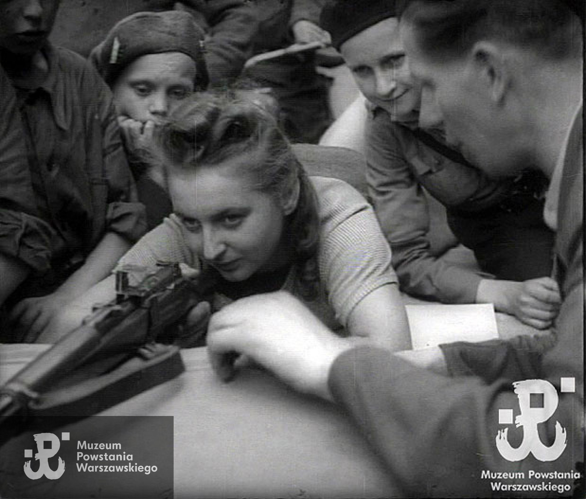 Kadr pochodzący zoryginalnych kronik z okresu Powstania Warszawskiego, przedstawiający naukę strzelania. Widoczna na fotografii dziewczyna do tej pory nie została zidentyfikowana, jednak według rozpoznania dokonanego przez córkę p. Zofii Ruzga - Narewskiej jest to jej mama. Wg wstępnej oceny p. Michała Wójciuka z Działu Historycznego MPW jest duże prawdopodobieństwo, że może być to ta sama osoba, jednak obecnie nie weryfikacja nie dobiegła końca