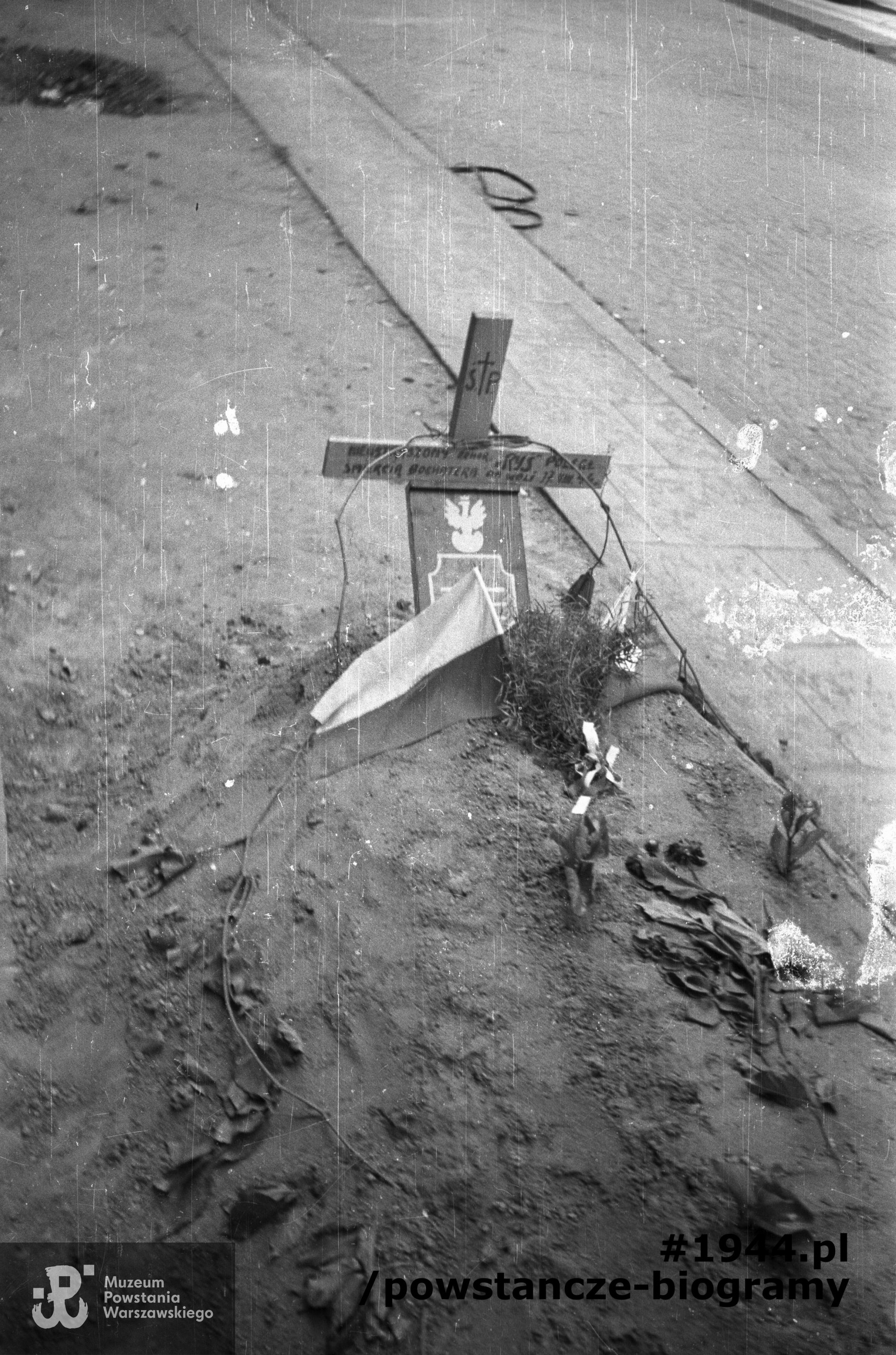 Fotografia z Powstania Warszawskiego. Mogiła kpr. pchor. Tadeusza Ryszarda Piotrowskiego "Rysia", żołnierza I Obwodu "Radwan" (oddział nieustalony), poległego 17 sierpnia 1944. Na grobie tabliczka z godłem, biało-czerwona flaga i tabliczka z godłem. Autorem zdjęcia jest Joachim Joachimczyk "Joachim". Ze zbiorów Muzeum Powstania Warszawskiego, sygn. MPW-IN/9992