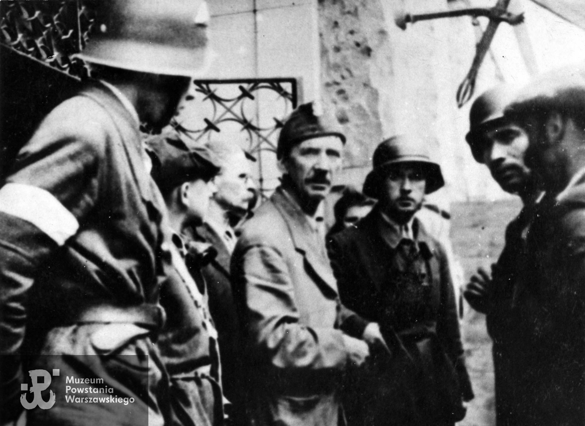 Fotografia z Powstania Warszawskiego. Śródmieście Północne. Żołnierze  "Leśnika" przed gmachem Sądu Grodzkiego na ul. Ogrodowej. Od lewej kolejno: NN, NN, mjr Adolf Łojkiewicz "Ryś", w furażerce ppłk Jan Szypowski "Leśnik", st. strz Kazimierz Rytel "Kazik", pchor. Marian Gorzkowski "Szary" i Stefan Kowalski "Jaroń" w cyklistówce. Fot. ze zbiorów Muzeum Powstania Warszawskiego, sygn. MPW-IK/1318