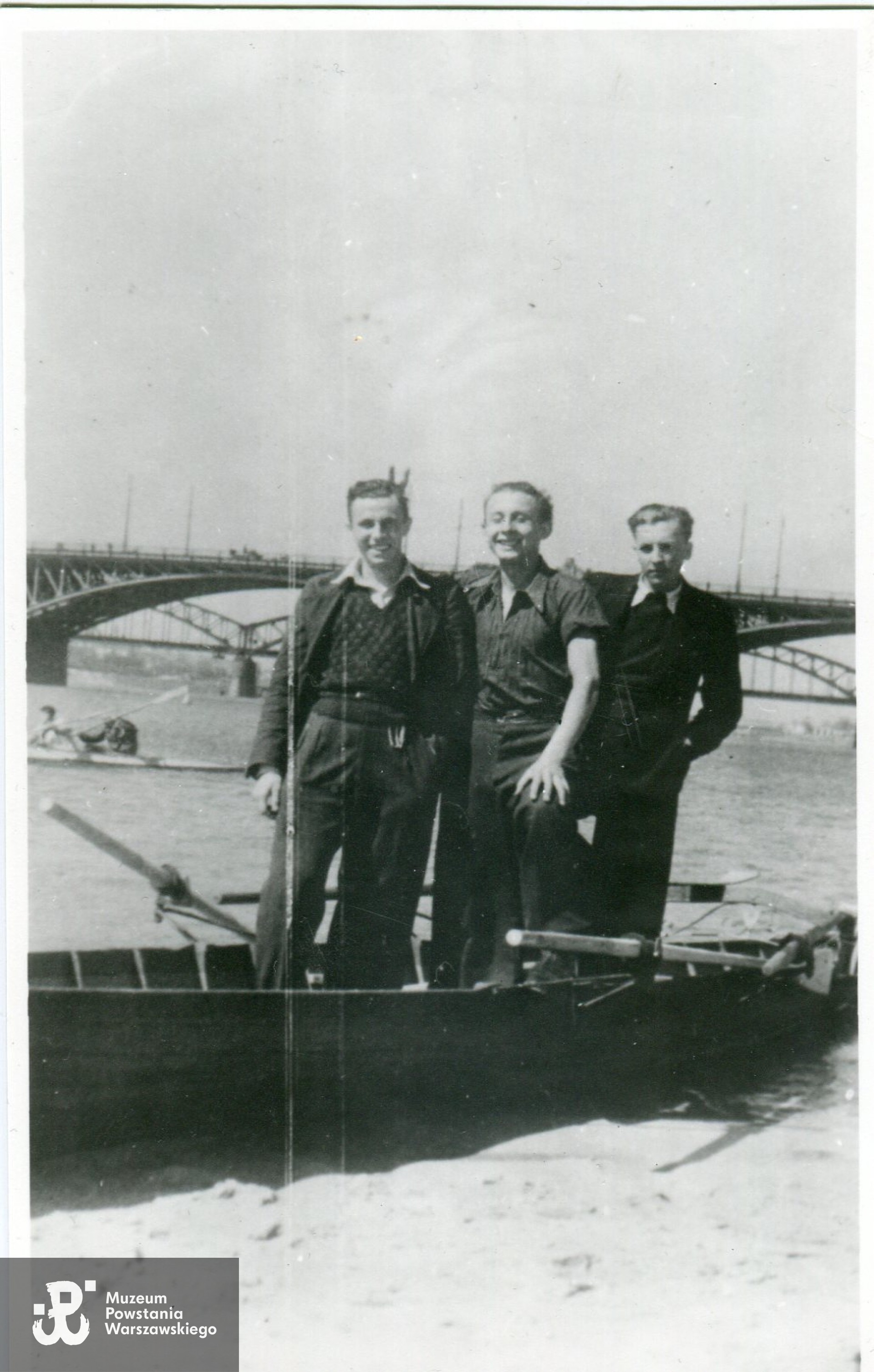 Fotografia wykonana w okresie okupacji niemieckiej, przed wybuchem Powstania Warszawskiego. Widok od strony Saskiej Kępy w kierunku mostów Poniatowskiego i średnicowego.  Na zdjęciu od lewej: Wiesław Gucman ps. Stefan, Edward Łopatecki ps. Młodzik, NN (również późniejszy powstaniec). Fot. ze zbiorów rodzinnych, skan udostępnił p. Krzysztof Gucman, syn Powstańca