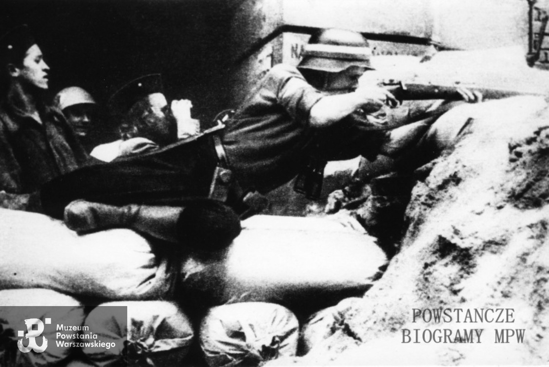 Początek sierpnia 1944 roku, Śródmieście, ul. Bracka. Żołnierze 3. kompanii Batalionu "Kiliński" na barykadzie przy bramie kamienicy Bracka 20. Z karabinem, w hełmie plut. pchor. Zygmunt Piotrowski "Władek", po lewej: strz. Władysław Aniołek "Kot", dziewczyna z lornetką: Maria Sileńska "Mery". Autor zdjęcia nieznany, fot. ze zbiorów MPW, sygn. MPW-IP/2377