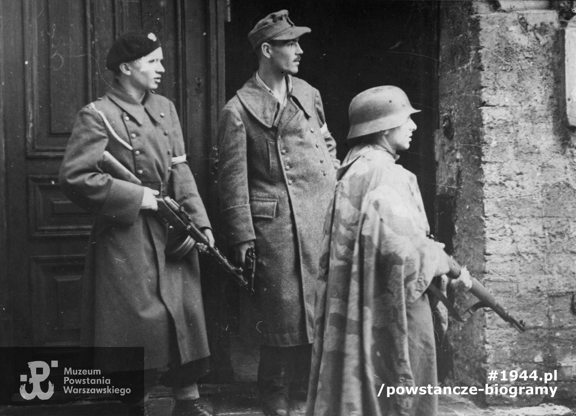 Fotografia z Powstania Warszawskiego. Śródmieście Północne. Trzech uzbrojonych powstańców z 3. kompanii Batalionu "Kiliński" przed wejściem do gimnazjum Wojciecha Górskiego przy ul. Górskiego 2.  Od lewej  strz. Maciej Strzyżewski "Genek" trzyma w rękach sowiecki pistolet maszynowy PPSz-41, tzw. pepesza, kpr. Wojciech Wyczański "Wojczan" oraz sap. Zbigniew Knotowski "Obowiązek" (w niemieckim płaszczu i hełmie). Zdjęcie ze zbiorów Muzeum Powstania Warszawskiego, sygn. MPW-IP/5989