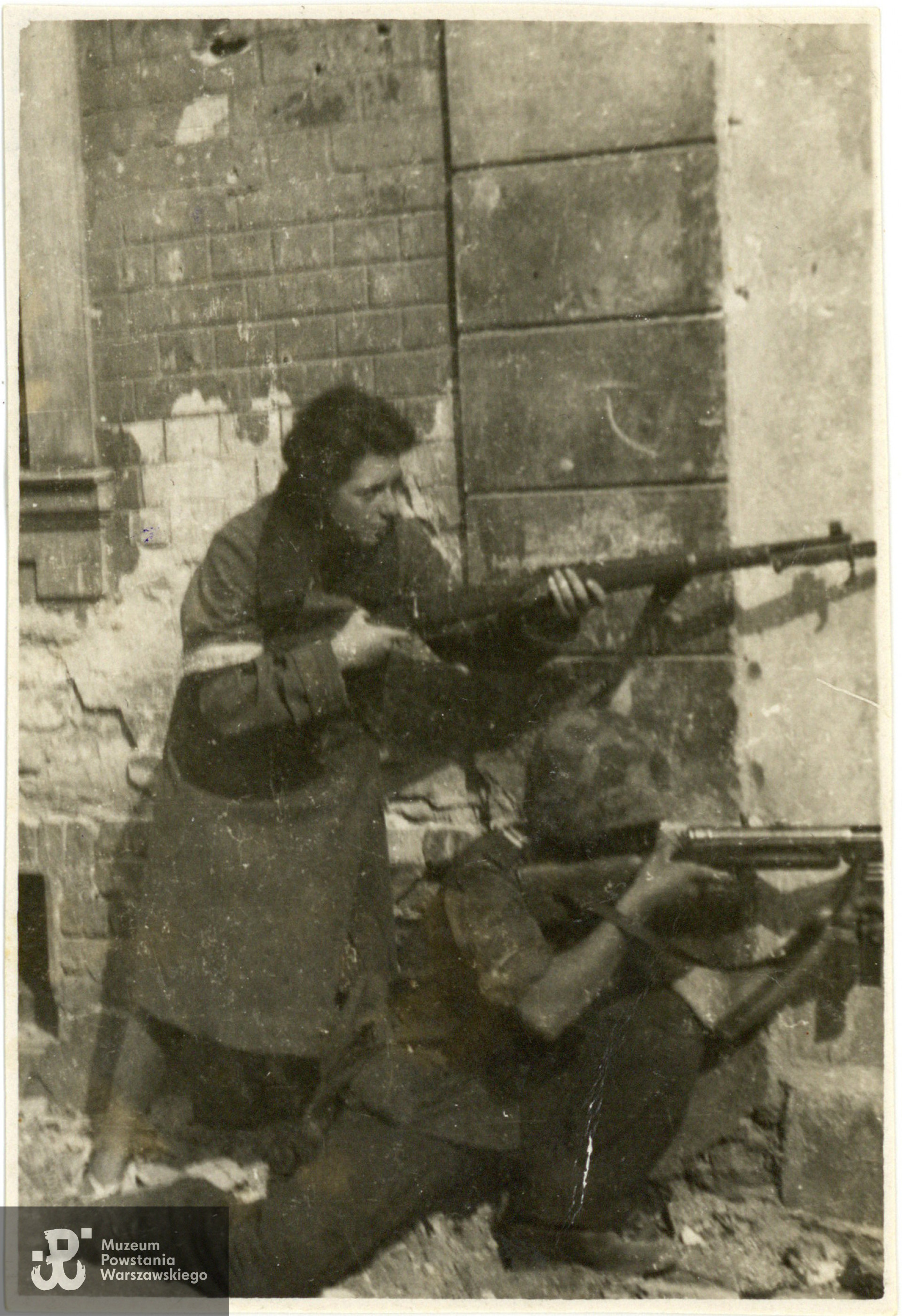 Fotografia  z okresu Powstania Warszawskiego pochodząca ze spuścizny po Adamie Zbigniewie Domańskim ps. Zbyszek. Śródmieście Południe, róg ul. Piusa XI (Pięknej) i Alej Ujazdowskich. Na zdjęciu żołnierze ze zgrupowania "Ruczaj" z kompanii "Habdank": łączniczka "Basia" - Barbara Mączyńska i strz. NN. Fotografia pochodzi ze spuścizny po Adamie Zbigniewie Domańskim, udostępniła p. Zofia Elżbieta Grzebalska z d. Domańska, córka Powstańca. Skany wykonano w Muzeum Powstania Warszawskiego w lutym 2024 r. 