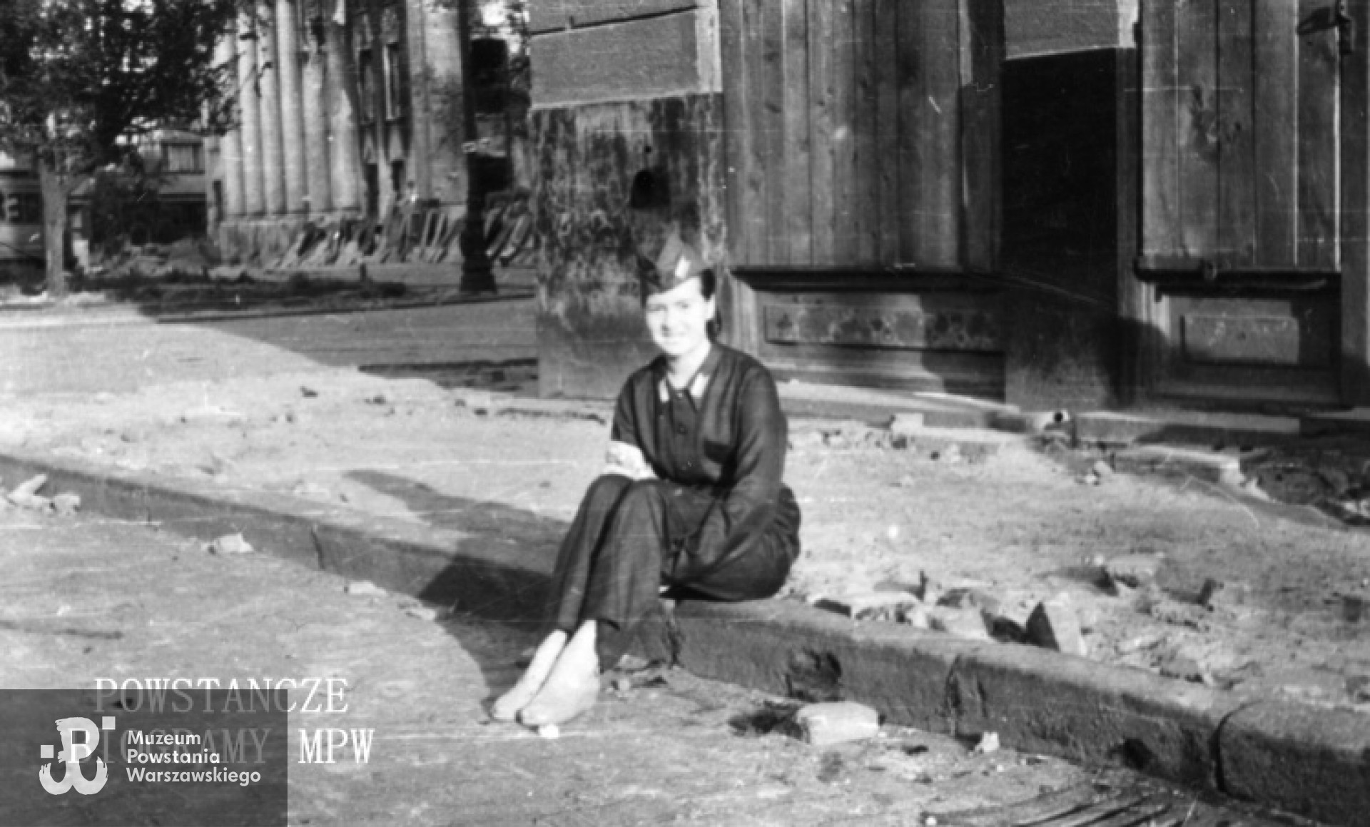 Fotografia z Powstania Warszawskiego. Śródmieście Południowe, rejon placu Trzech Krzyży. Maria Marczyńska - Robowska "Leszkowa" lekarka punktu sanitarnego przy ul. Sosnowej 3 siedząca na krawężniku. Fot. ze zbiorów Muzeum Powstania Warszawskiego, sygn. MPW-IK/2399. Dar Anny Kuczyńskiej