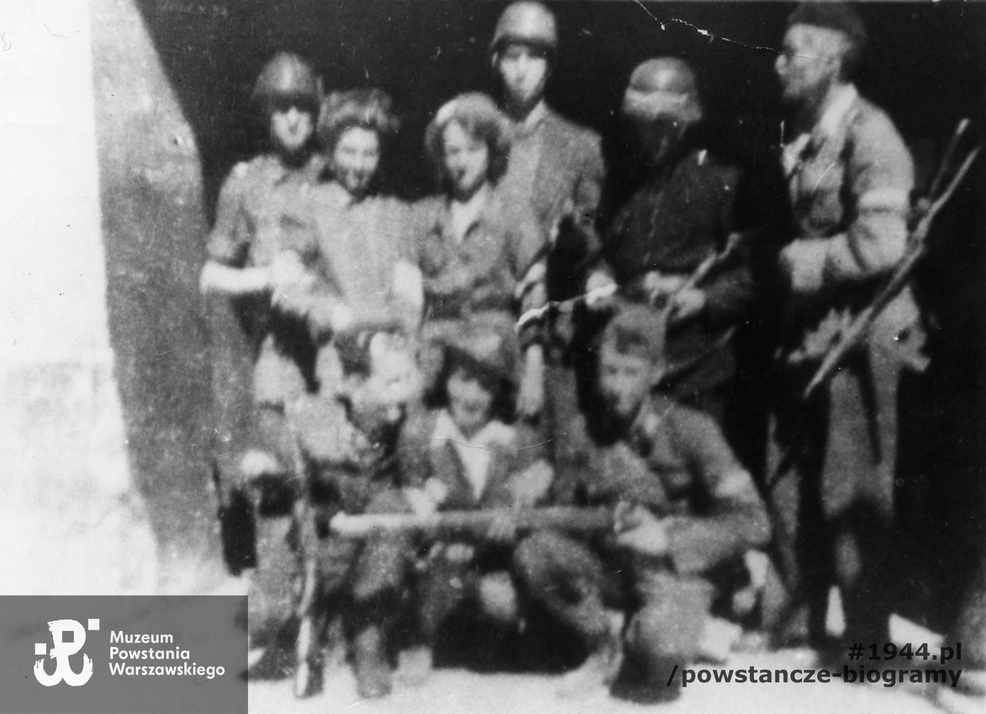 Fotografia z Powstania Warszawskiego. Śródmieście Północne. Powstańcy Batalionu "Kiliński" w bramie domu przy ul. Królewskiej 16. Stoją od lewej : NN, strz. Krystyna Wyderko "Wydra", sanitariuszka Jadwiga Wiktorowska-Somczyńska "Słowianka", kpr. Zenon Somczyński "Słaby"; w środku kuca "Janka". Wśród nierozpoznanych osób: st. strz. Zygmunt Andrzejewski "Andrzej", sierż. Marian Witkowski "Wtorek", kpr. pchor. Bernard Antoni Zieliński "Połabski", plut. Jan Waliński "Skowronek", kpr. Witold Janikowski "Vis". Fotografia ze zbiorów Muzeum Powstania Warszawskiego, sygn. MPW-IP/5921