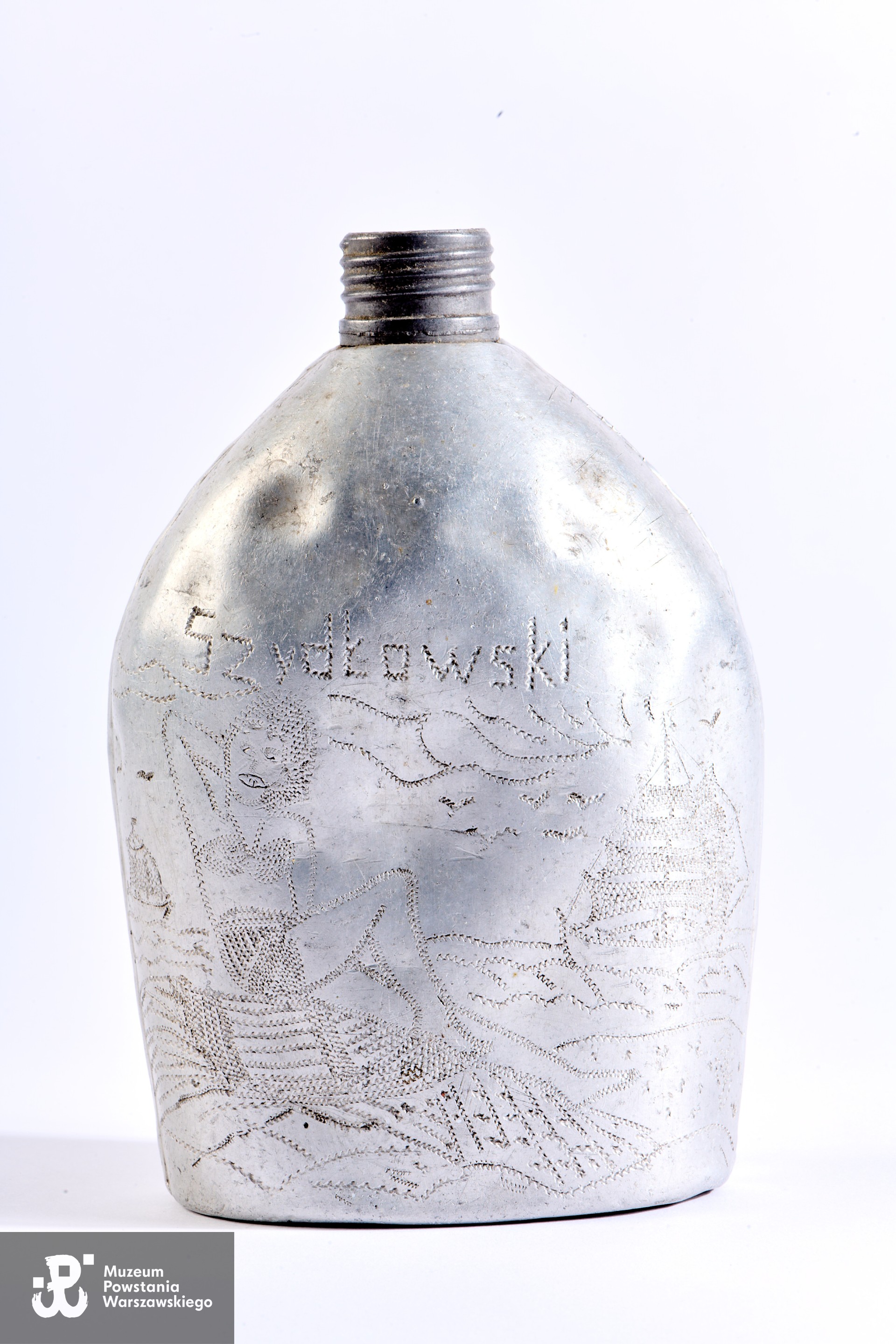 Manierka należąca do Stanisława Szydłowskiego, ozdobiona przez niego przedstawieniami młodych kobiet bawiących się na plaży. Otrzymana prawdopodobnie po wyzwoleniu z niewoli w obozie jenieckim Stalag XI A Altengrabow, w ramach którego Stanisław Szydłowski został przydzielony do pracy w  Kommando 274/1 Gatersleben (cukrownia Zuckerfabrik Gatersleben). Według wstępnych ustaleń MPW Stanisław Szydłowski, wraz z innymi jeńcami pracującymi w/w fabryce,  w momencie zbliżania się wojsk alianckich został prawdopodobnie przewieziony do miejscowości Staßfurt, gdzie 12.04.1945 roku nastąpiło wyzwolenie przez armię amerykańską. Później przebywał w obozie przejściowym w Allendorf.  