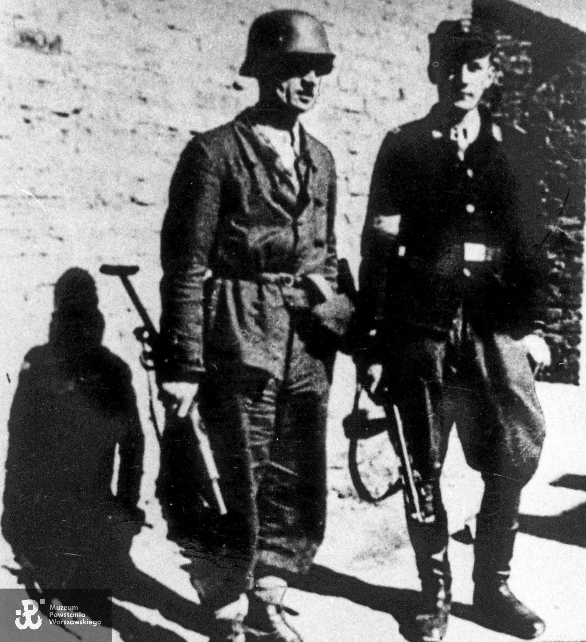 Fotografia z Powstania Warszawskiego. Śródmieście Północne. Żołnierze IV Zgrupowania "Gurt" - 3. kompania, pluton 144 - 145. Z lewej plut. Marian Adamkiewicz "Potok", obok kpr. pchor. Mieczysław Budziński "Miecz". Na zdjęciu widoczne pistolety maszynowe Sten. Fot. ze zbiorów Muzeum Powstania Warszawskiego, sygn. MPW-IH/1555