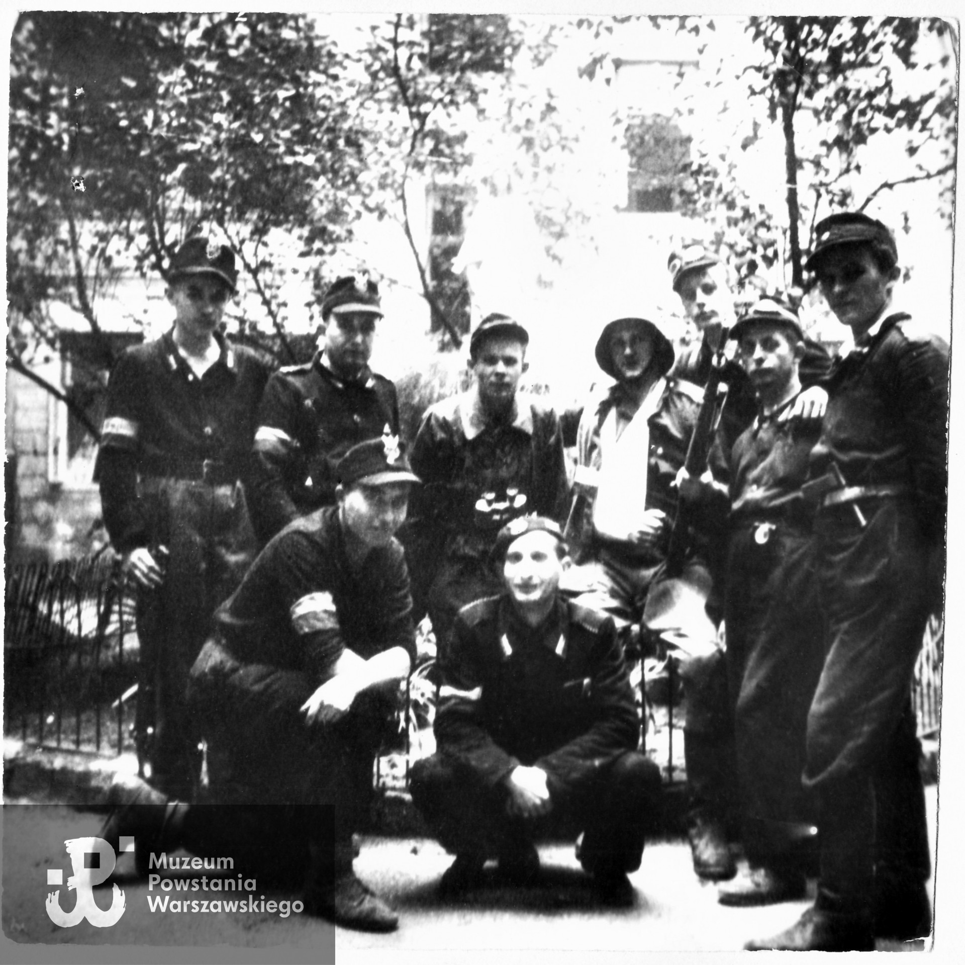 Fotografia z Powstania Warszawskiego. Śródmieście Północne. Powstańcy z 193 plutonu  Kompanii zgrupowania "Gurt" na podwórzu kamienicy przy ul. Chmielnej 64 około 20 sierpnia 1944 r.  Pierwszy od lewej stoi  strz. Andrzej Trubecki ps. Zając, następnie kpr. "Pancernik" (NN), por. Fryderyk Fryszer ps. Pilot,  pchor. Zbigniew Słupnicki [sic!] ps. Jasieńczyk [„Jesiończyk” - przyp. red.], były dowódca plutonu,  st. strz. "Sęp" (NN), Mieczysław Szmidt ps. Mietek, sierż. Ludwik Mizerski  ps. Karol. Klęczą od lewej:  strz. "Kuternoga" (NN) i st. z cenz. "Okularnik". Fot. ze zbiorów p. Andrzeja Trubeckiego ps. Zając, ujęcie tożsame w zbiorach Muzeum Powstania Warszawskiego, sygn. MPW-IH/139, MPW-IH/1563 oraz MPW-IP/3285