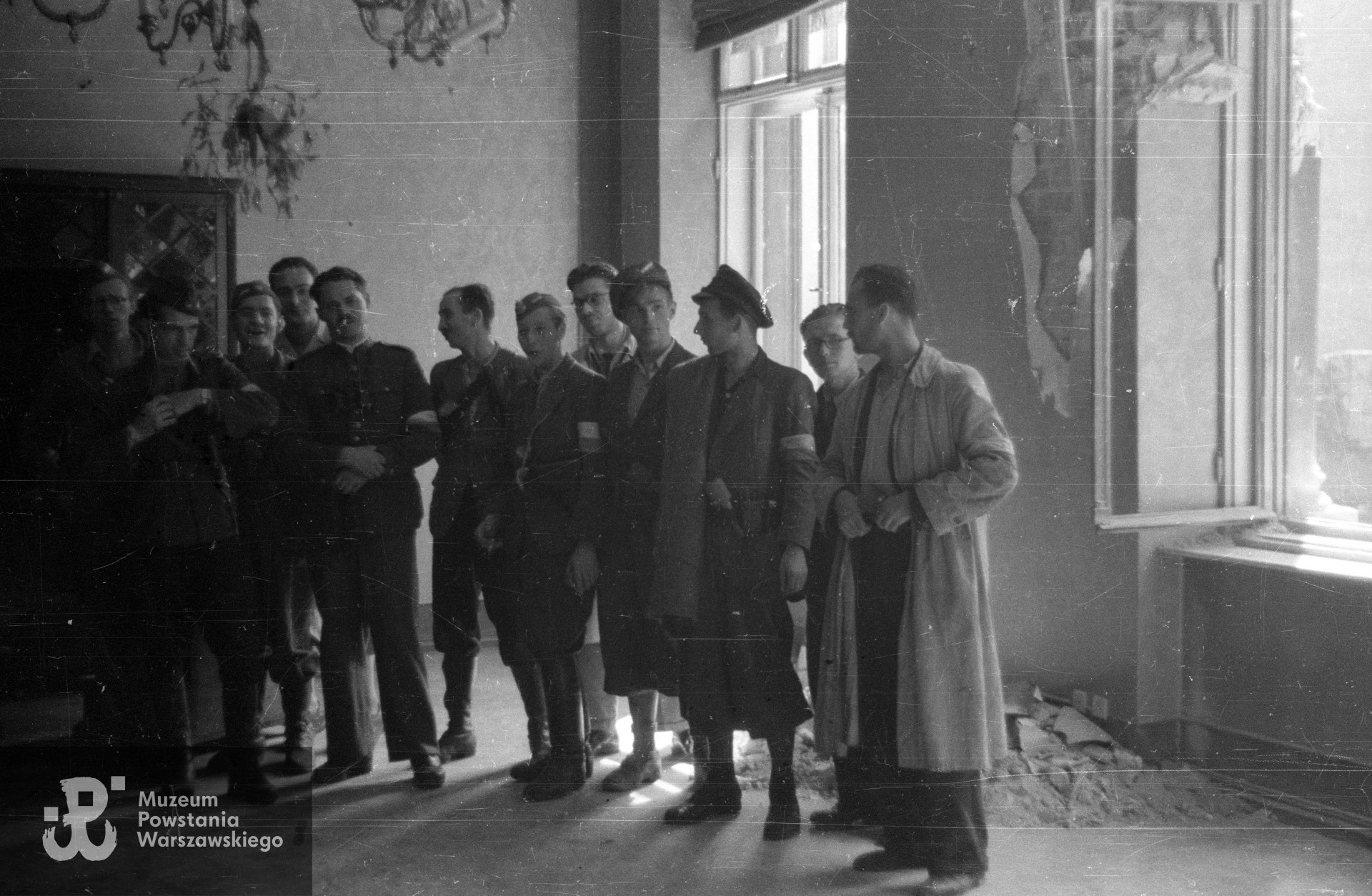 Fotografia z Powstania Warszawskiego. Żołnierze z kompanii "Grażyna" Batalionu "Harnaś" w kwaterze przy ulicy Mazowieckiej 4. Od lewej: kpr. Stefan Medwadowski "Poraj", kpr. pchor. Ryszard Benedykciński "Niesiołowski", ppor. Konrad Niklewicz "Konrad", NN, por. Marian Krawczyk "Harnaś", ppor. Zbigniew Siciński "Kazimierz", plut. pchor. Bolesław Koucki "Kocio", NN, NN, NN, NN, NN. Fot. ze zbiorów Muzeum Powstania Warszawskiego, sygn. MPW-IN/3258