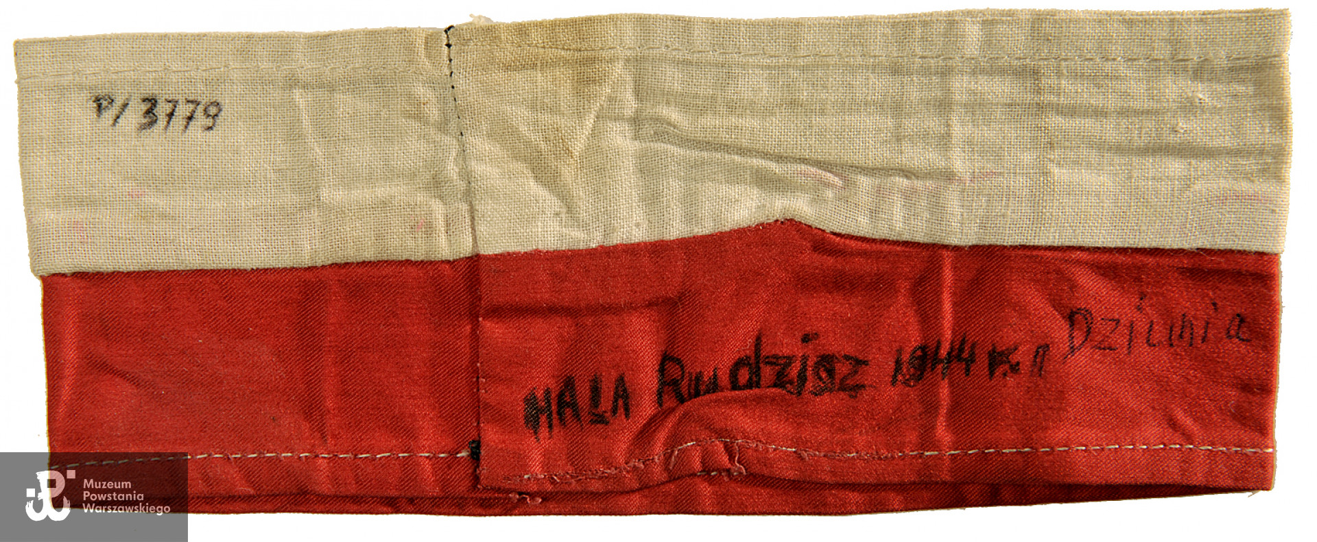 Biało - czerwona opaska powstańcza,  należąca do szer. Haliny Bożeny Rudziszówny - Gonerko ps. "Dziunia"," Audaniec". Na opasce nadruk WP pomiędzy literami nadruk orła w koronie( polskie godło). Opaska zszyta, na odwrotnej stronie napis odręczny: Hala Rudzisz 1944 PS. "Dziunia". Ze zbiorów Muzeum Powstania Warszawskiego.