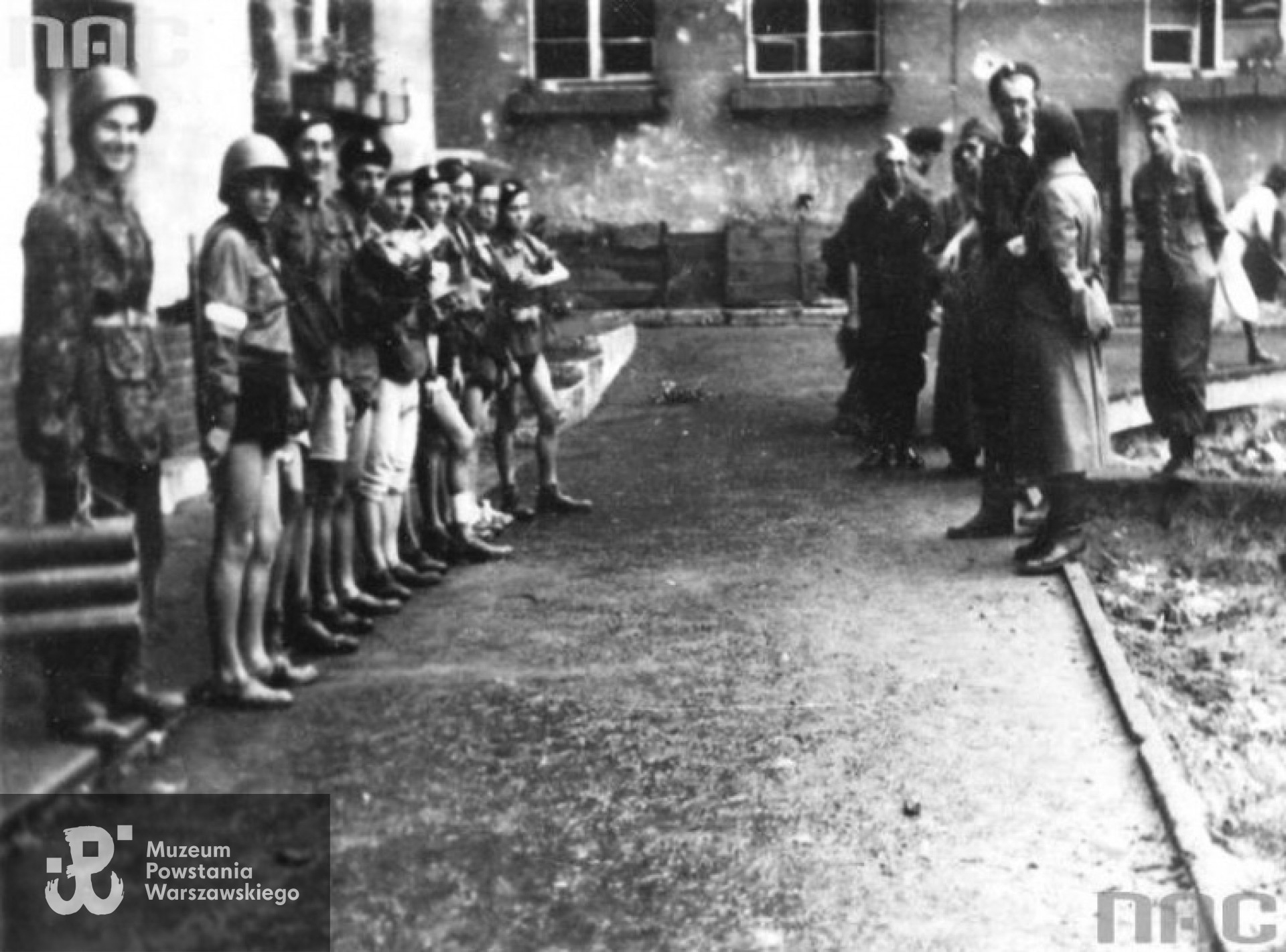 Fotografia z okresu Powstania Warszawskiego. Powstańcy przenoszący kanałami pocztę, broń i amunicję z Żoliborza na Starówkę. Stoją od lewej: Wiesław Czajczyński ps. "Robert", Andrzej Lendzion ps. "Zenek", Czesław Nowak ps. "Korczak", Stefan Marcjanek ps. "Ostoja", NN przewodnik kanałowy ze Starówki, Janusz Przybysz ps. "Lis", Wiesław Golat ps. "Ryś", Jan Szewczyk ps. "Jopek", Romuald Augustyniak ps. "Upiór". Archiwum Fotograficzne Stefana Bałuka, zbiory NAC, www.audiovis.nac.gov.pl