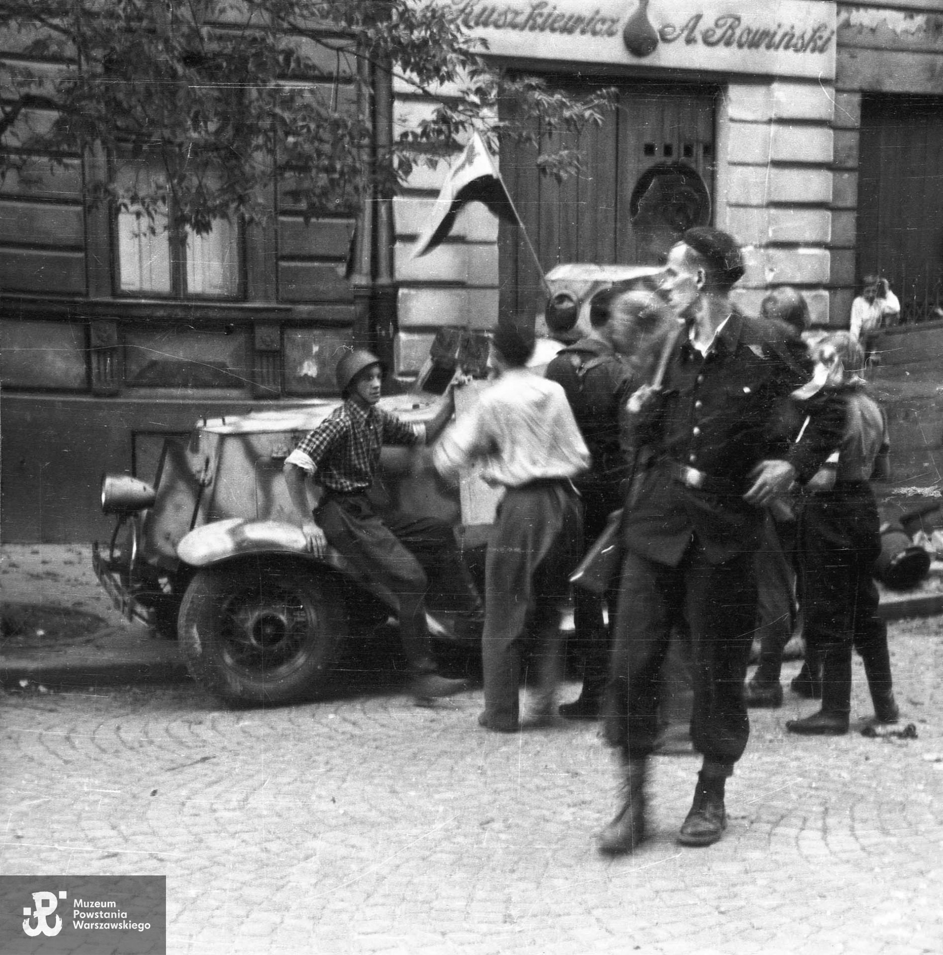 Fotografia z Powstania Warszawskiego. Zdobyty przez Powstańców samochód opancerzony na ul. Kruczej na styku kamienic nr 3 i 5. Na pojeździe zamocowana biało-czerwona flaga. Przy pojeździe grupa mężczyzn,  jeden z nich w charakterystycznej koszuli w kratę, jakie często nosili żołnierze Batalionu "Ruczaj".  Nad zabitym deskami oknem sklepu częściowo widoczny szyld "[Rusz]kiewicz / A. Rowiński". Na pierwszym planie Wojciech Tabaczkiewicz "Narwicz". Autorem zdjęcia jest Stanisław Dobrzyński. Fot. ze zbiorów Muzeum Powstania Warszawskiego, sygn. MPW-IH/1766. Identyfikacji Wojciecha Tabaczkiewicza ps. Narwicz dokonała p.  Barbara Lulińska, siostra cioteczna Powstańca.
