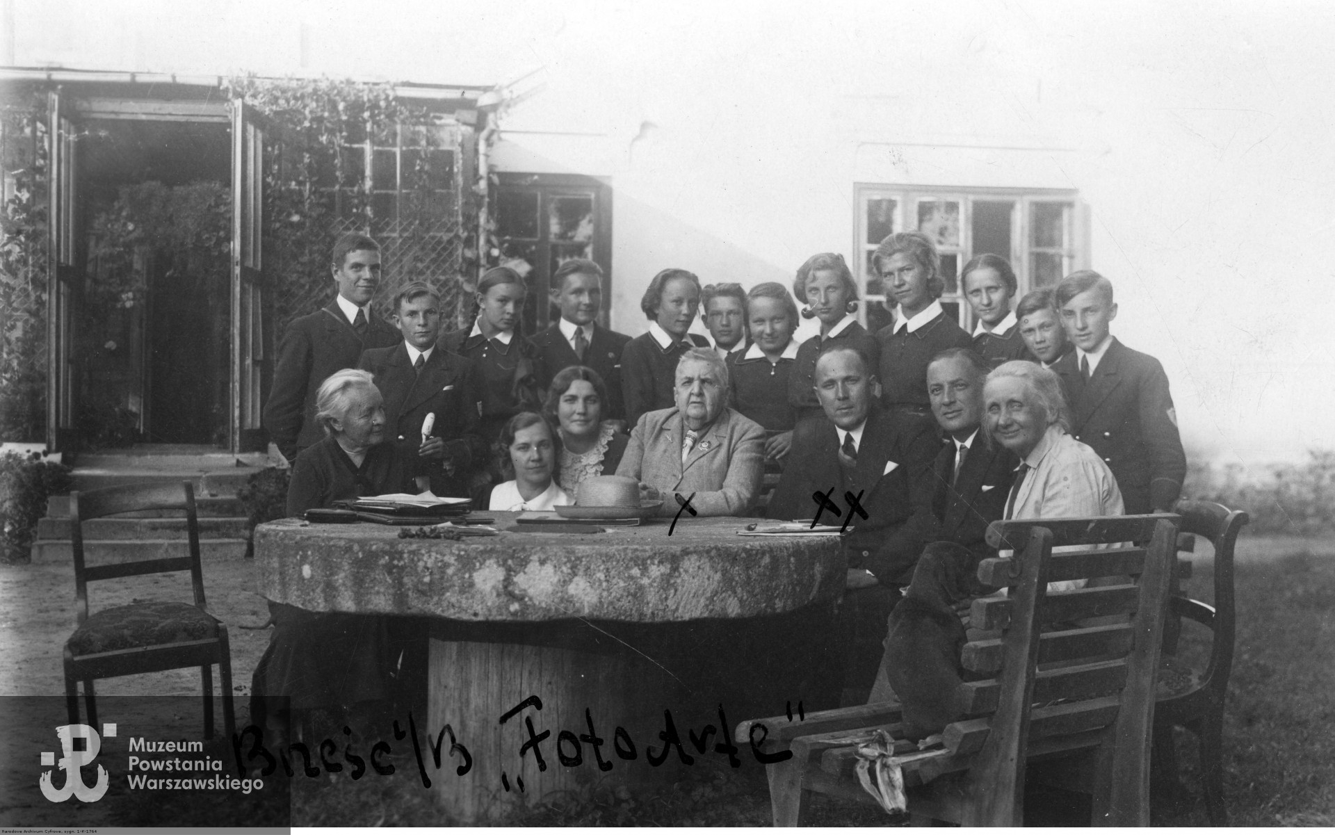 1937 rok - Maria Rodziewiczówna (siedzi czwarta z prawej) przed swoim domem w Hruszowie w otoczeniu nauczycieli i młodzieży z gimnazjum kupieckiego w Brześciu nad Bugiem. Ze zbiorów Narodowego Archiwum Cyfrowego - Koncern Ilustrowany Kurier Codzienny - Archiwum Ilustracji, audiovis.nac.gov.pl