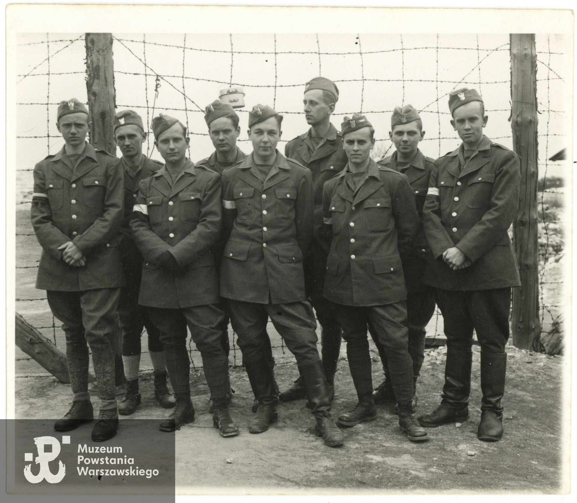 Żołnierze z Polskiego Ośrodka Wojskowego w Bad Harzburg na terenie byłego obozu w Harlingerode, kwiecień 1945 roku. Od lewej: 1) Stefan Medwadowski „Poraj”/”Medor”, 2) Andrzej Ligęza "Cowboy", 3) Ryszard Rosmański "Ryszard",  4) Maciej Czerski "Kot", 5) Henryk Kazimierz Pieńkowski "Kazik", 6) Zygmunt Raczyński „Zygmuś", 7) Zdzisław Krzyżanowski „Żbik”, 8) Michał Horoszewicz „Michał” i 9) Zdzisław Ludwik Szeliski "Zdziś". Fotografia pochodzi ze spuścizny po Zygmuncie Janie Raczyńskim ps. Zygmuś, zbiory rodzinne p. Jerzego Raczyńskiego, syna Powstańca