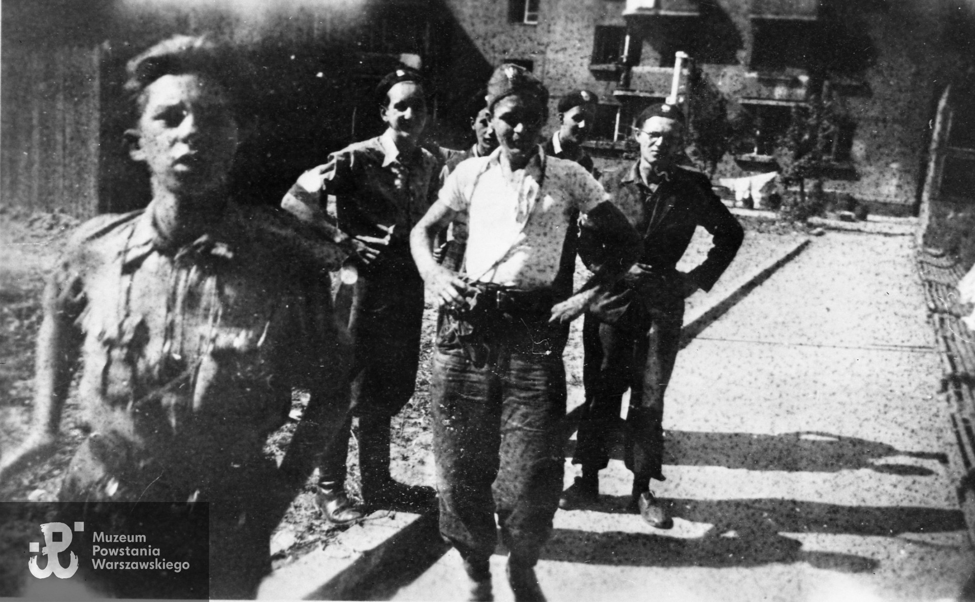 Fotografia z Powstania Warszawskiego. Żoliborz, zgrupowanie "Żyrafa". Harcerze z plutonu 227 na podwórzu bloku przy ul. Krasińskiego 20. Od lewej: strz. Włodzimierz Krystasiak "Mongoł", strz. Józef Małkowski "Sokół", strz. Wiesław Nowak "Jastrząb", NN, strz. Zbigniew Kamiński "Złamaniec". Fot. ze zbiorów Muzeum Powstania Warszawskiego, sygn. MPW-IH/5396. Ujęcie tożsame w zbiorach rodzinnych pp. Małkowskich - wydruk w teczkach personalnych Uczestników Powstania Warszawskiego: Małkowski Józef. 
