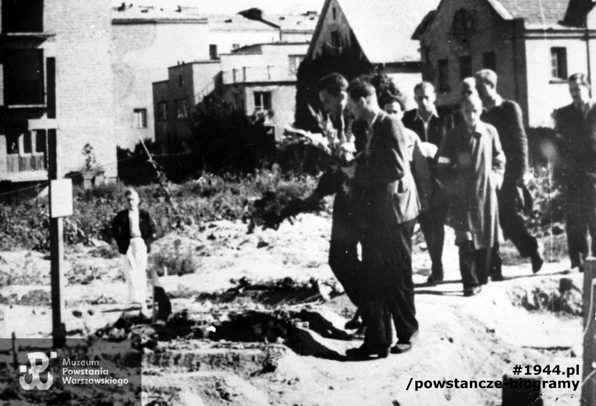  Zdjęcie autorstwa Romana Banacha ps. "Świerk". Mokotów, cmentarz powstańczy przy Szpitalu Elżbietanek w rogu ulic Goszczyńskiego i Tynieckiej. W tle budynku przy ulicy Tynieckiej. Grupa powstańców z Grupy Artyleryjskiej "Granat" idzie z kwiatami na grób dowódcy, mjr art. Józef Szyszko "Bachmat", który zginął 13 sierpnia. Ze zbiorów Muzeum Powstania Warszawskiego, sygn. MPW-IH/1216