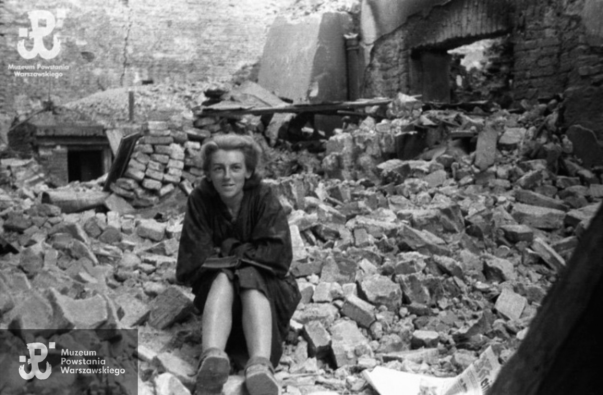 Powstanie Warszawskie, sierpień, Stare Miasto. Sanitariuszka Danuta Magreczyńska "Danka” z kompanii "Anna” batalionu "Gustaw” z książką na gruzach domu przy ulicy Ślepej. Po prawej stronie pozostałości po kamienicy z przejściem na stronę Podwala. Fot. Wiesław Chrzanowski "Wiesław", zbiory Fototeki MPW, sygn. MPW-IN/3255