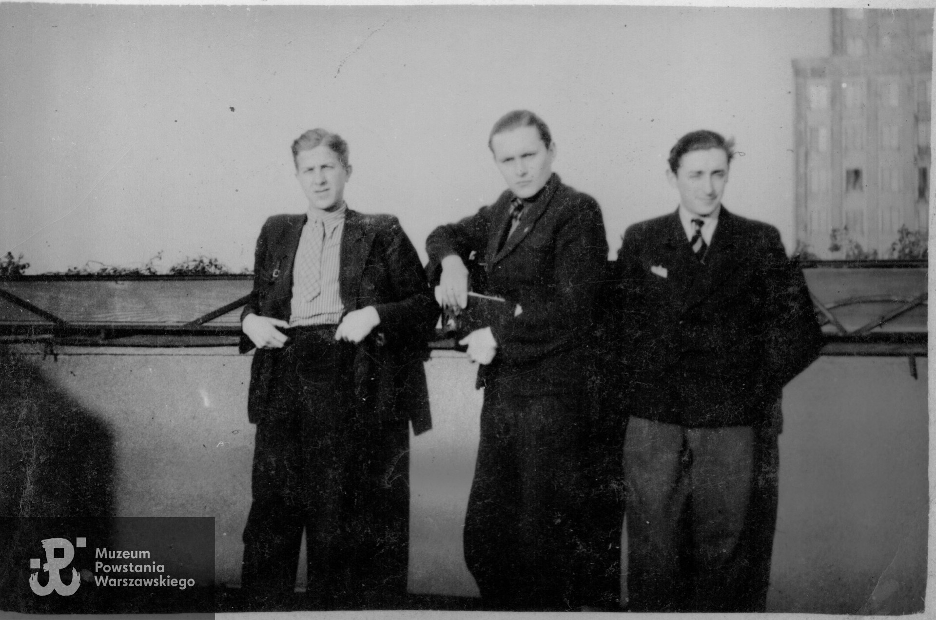 Zygmunt Kafarowski  (pierwszy z lewej strony) z kolegami. Warszawa, rok nieustalony. W prawym górnym rogu fotografii widoczny gmach Towarzystwa Ubezpieczeń "Prudential" przy placu Napoleona 9, poważnie zniszczony w okresie Powstania Warszawskiego. Fot. ze zbiorów rodzinnych, udostępniła dr Joanna Kafarowski
