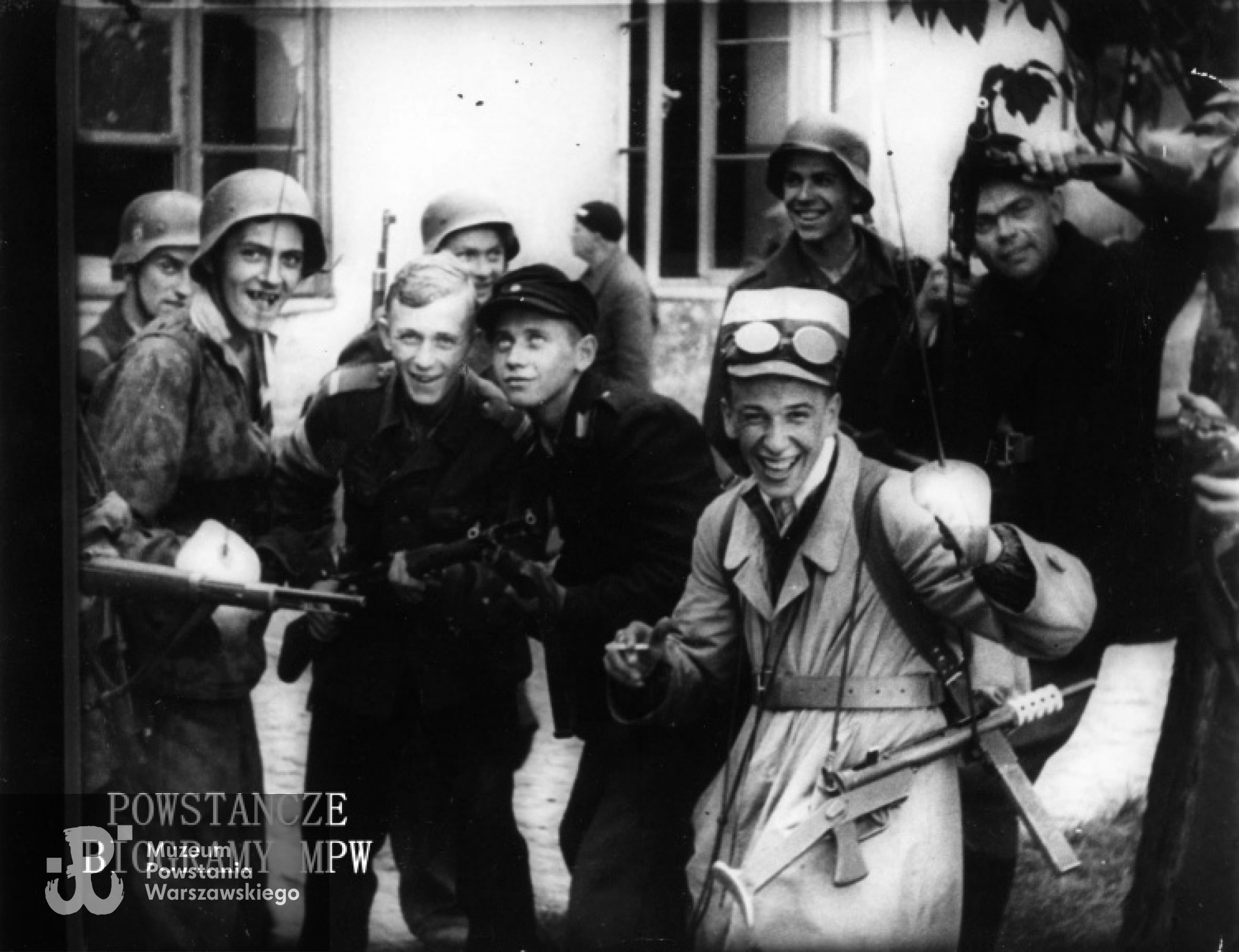 Fotografia filmowa z Powstania Warszawskiego. Śródmieście Północne. Powstańcy ze zgrupowania "Harnaś" po zdobyciu Komendy Policji na Krakowskim Przedmieściu. W jasnym płaszczu ppor. Jerzy Zamecki "Wilczek". Pośród Powstańców także Władysław Wojewódzki. Ze zbiorów Muzeum Powstania Warszawskiego, sygn. MPW-IP/2099