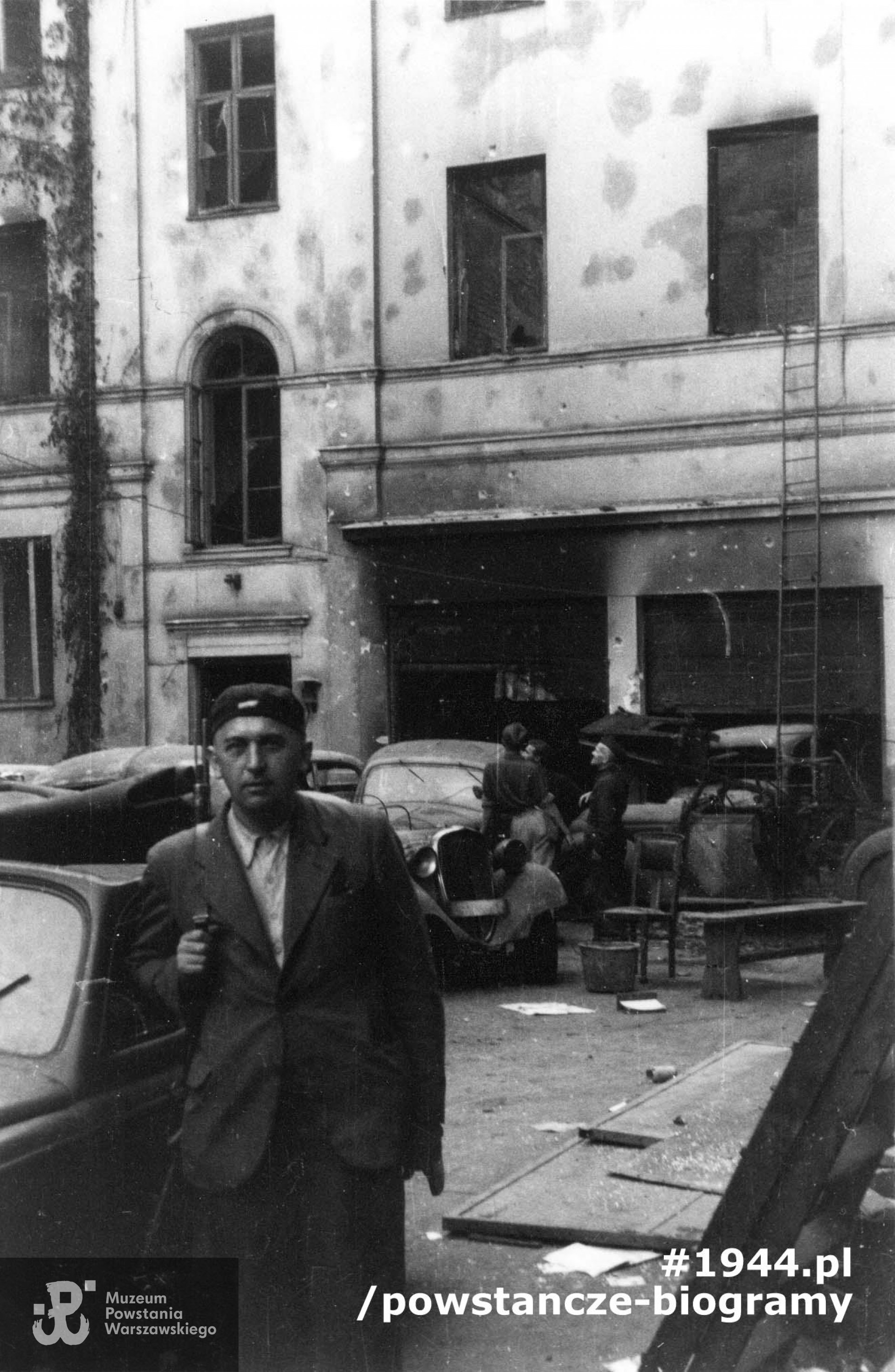 Fotografia z Powstania Warszawskiego. Śródmieście Południowe. Dziedziniec "Małej PAST-y" na ul. Piusa XI (ob. Pięknej) w dzień po jej zdobyciu. Przy samochodzie ppor. Henryk Rusinowski "Huragan" dowódca plut. 150 w  5.  kompanii Batalionu "Golski". Autorem zdjęcia jest Andrzej Bargiełowski "Stańczyk". Fot. ze zbiorów Muzeum Powstania Warszawskiego, sygn. MPW-IN/898