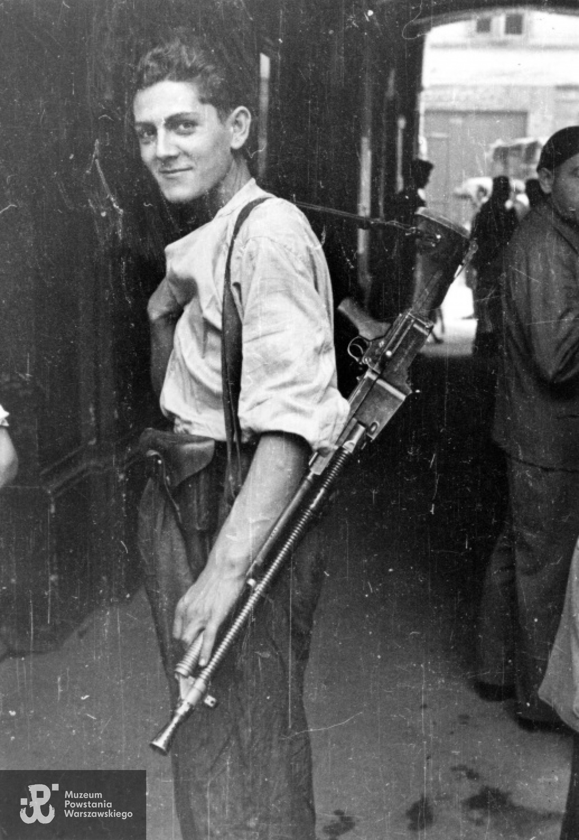 Fotografia z Powstania Warszawskiego autorstwa Eugeniusza Lokajskiego. Śródmieście Północne. Plut. pchor. Włodzimierz Wiśniewski "Cygan" z kompanii "Janusza" z Batalionu "Harnaś" stojący w bramie kamienicy z ręcznym karabinem maszynowym Cz Zbrojovka wz. 26 ze zrzutu. Data wykonania zdjęcia:  3 dekada sierpnia 1944, prawa autorskie: MPW. Zbiory Fototeki MPW, sygn. MPW-IN/733