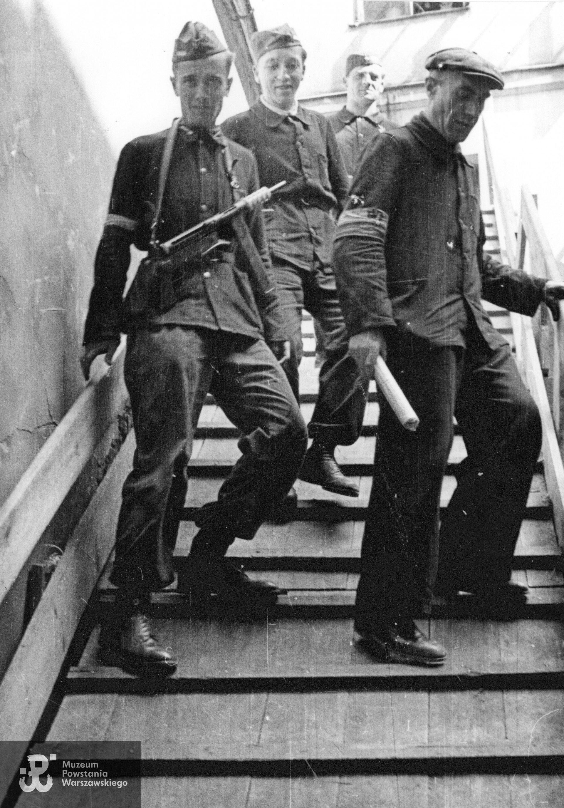 III dekada sierpnia : Śródmieście Północne. Grupa powstańców z Oddziału Osłonowego WZW schodząca po prowizorycznych schodach; od lewej: kpr. pchor. Antoni Nałęcz "Toni", strz. Marian Kakowski "Maniuś", (prawdopodobnie) por. Stefan Berent "Steb" i st. wachm. Roch Kafarowski "Ksawery". Fot. ze zbiorów Muzeum Powstania Warszawskiego, sygn. MPW-IN/698, autorem zdjęcia jest Eugeniusz Lokajski "Brok". 