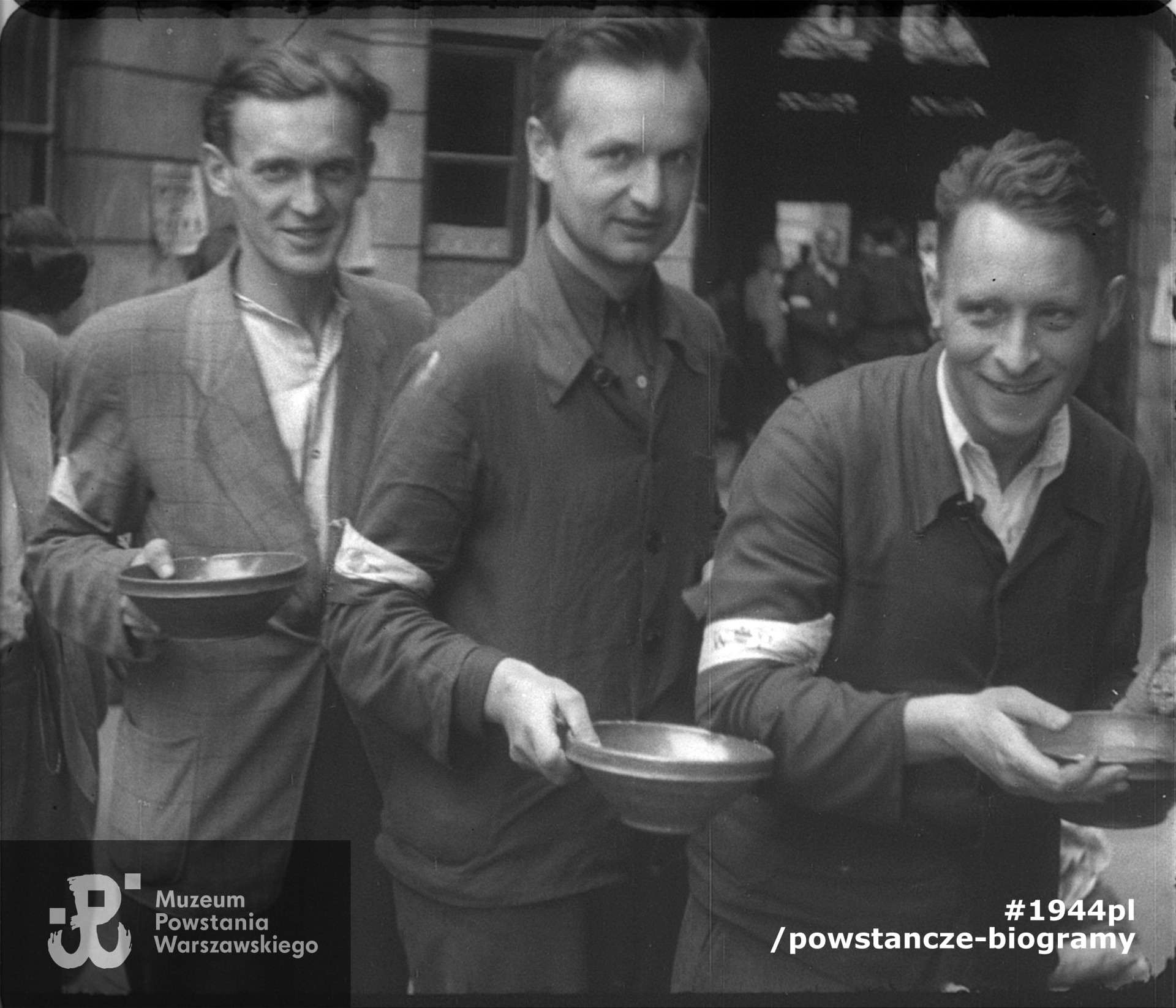 Stołówka powstańcza na podwórzu kamienicy przy ul. Szpitalnej 8. Od lewej: kpr. pchor. Bernard Wojciech Mencel „Paweł”, członek patrolu megafonowego „Chwaty” (poległ 13.09.1944 r. przy ul. Marszałkowskiej),  por. Józef Marian Sosnowski, ps. Brzeziński, Tadeusz Mikulski „Krasicki”. Zdjęcie filmowe z okresu Powstania. Ze zbiorów Muzeum Powstania Warszawskiego.