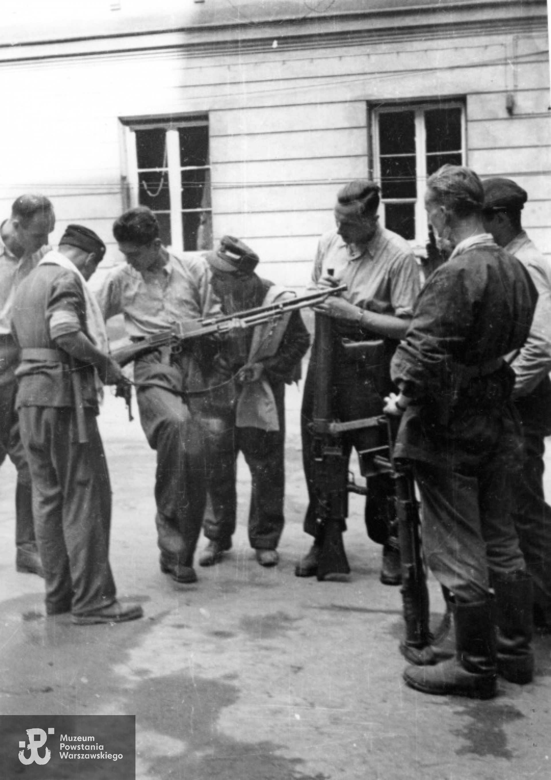 Kpr. pchor. Włodzimierz Wiśniewski "Cygan" z kompanii "Janusza" z Batalionu "Harnaś" pokazujący kolegom ręczny karabin maszynowy Cz Zbrojovka wz. 26 ze zrzutu. Trzeci od prawej stoi plut. pchor. Adam Podkóliński "Michał" (w jasnej koszuli) z opartym o ziemię niemieckim lekkim karabinem maszynowym - leMG 08/15. Fotografia autorstwa Eugeniusza Lokajskiego, prawa autorskie: MPW. Zbiory Fototeki MPW, sygn. MPW-IN/729