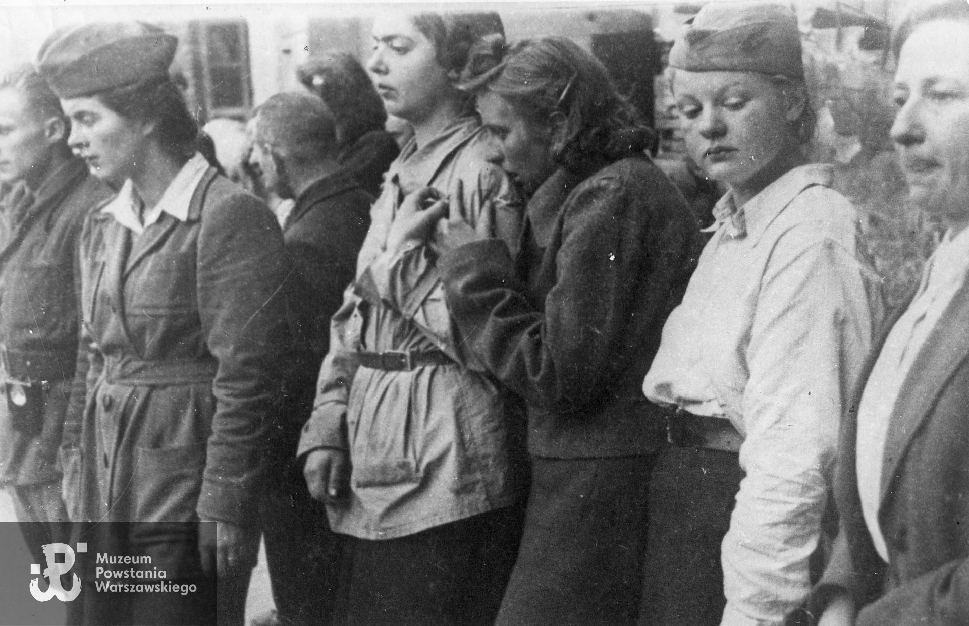 Fotografia z Powstania Warszawskiego. Śródmieście Północne - sierpień 1944.  Sanitariuszki z Kompanii Szturmowej "Stefan" zgromadzone na pogrzebie na terenie obok ruin kina "Capitol" na tyłach kamienicy przy ul. Marszałkowskiej 125. Druga od prawej sanit. Danuta Zakrzewska "Danka", pierwsza od lewej sanit. Anna Tellen-Wilczyńska "Żaba". Fot. autorstwa Zygmunta Kukieły ps. "Zetka" ze zbiorów Muzeum Powstania Warszawskiego, sygn. MPW-IP/2480 