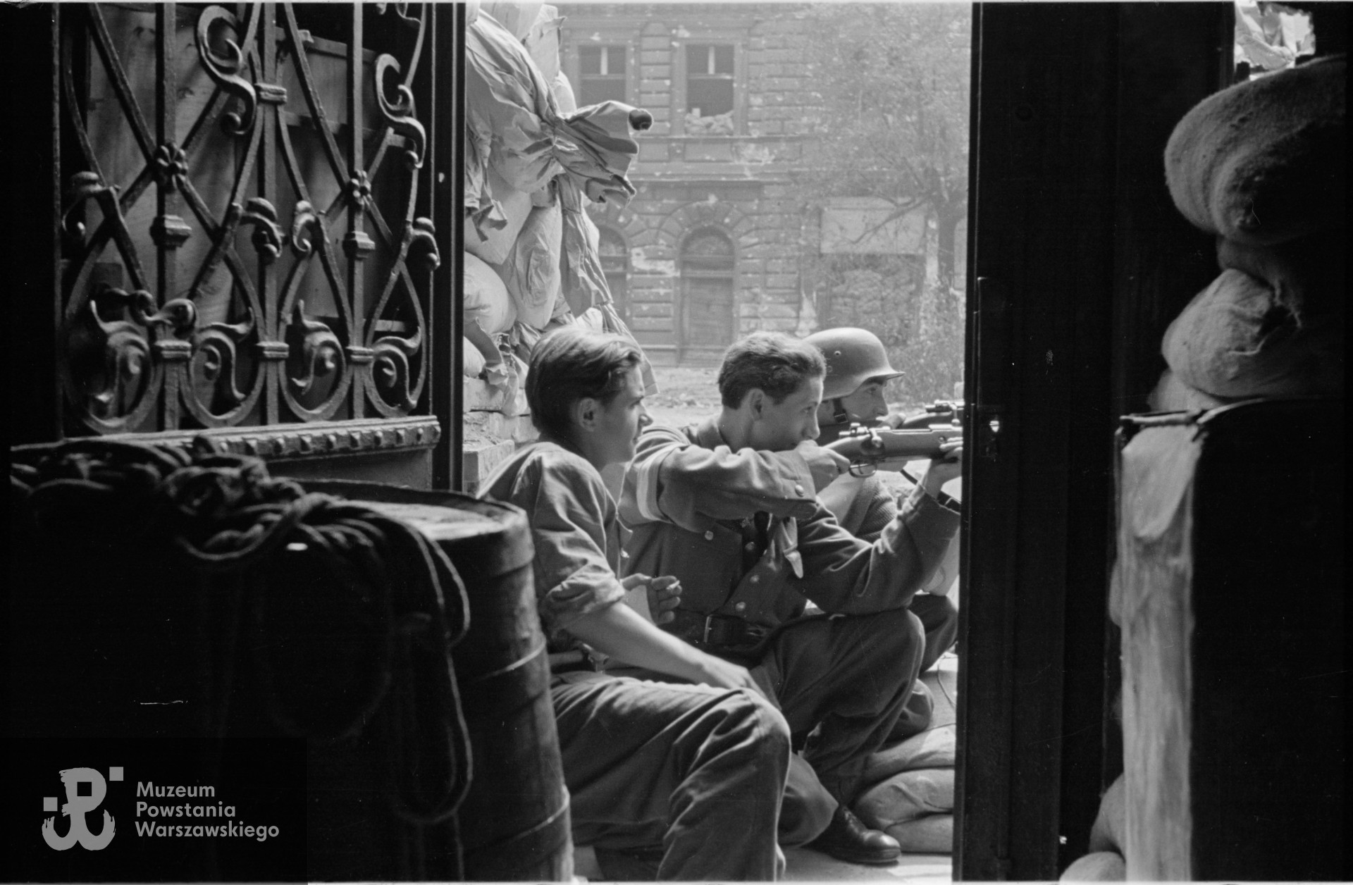 Fotografia z Powstania Warszawskiego, przyczółek barykady w Alejach Jerozolimskich 22, Siedzą od lewej:  st. strz. z cenz. Tadeusz Zapałowski ps. Michał, strz. Mieczysław Danis „Olgierd” i  st. strz. Ryszard Szymczak „Czarny". Ze zbiorów Muzeum Powstania Warszawskiego, sygn. MPW-IS/2837